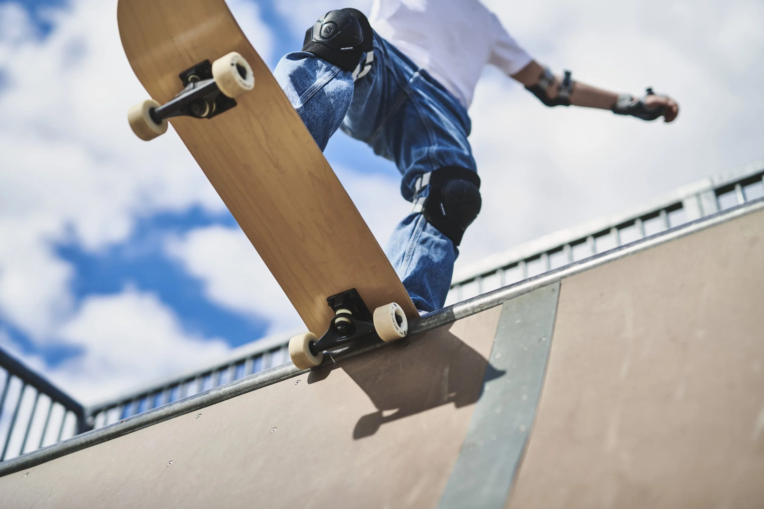 En person gør tricks på en skateboard i en skatepark, set udefra og nedenfra.