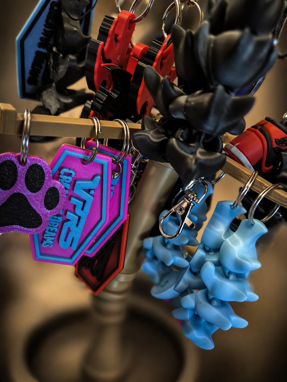 Keychain holder with colorful pet tags and accessories, including purple paw print tag, pink and blue tags, black rubber items, and blue rubber flower-shaped items.