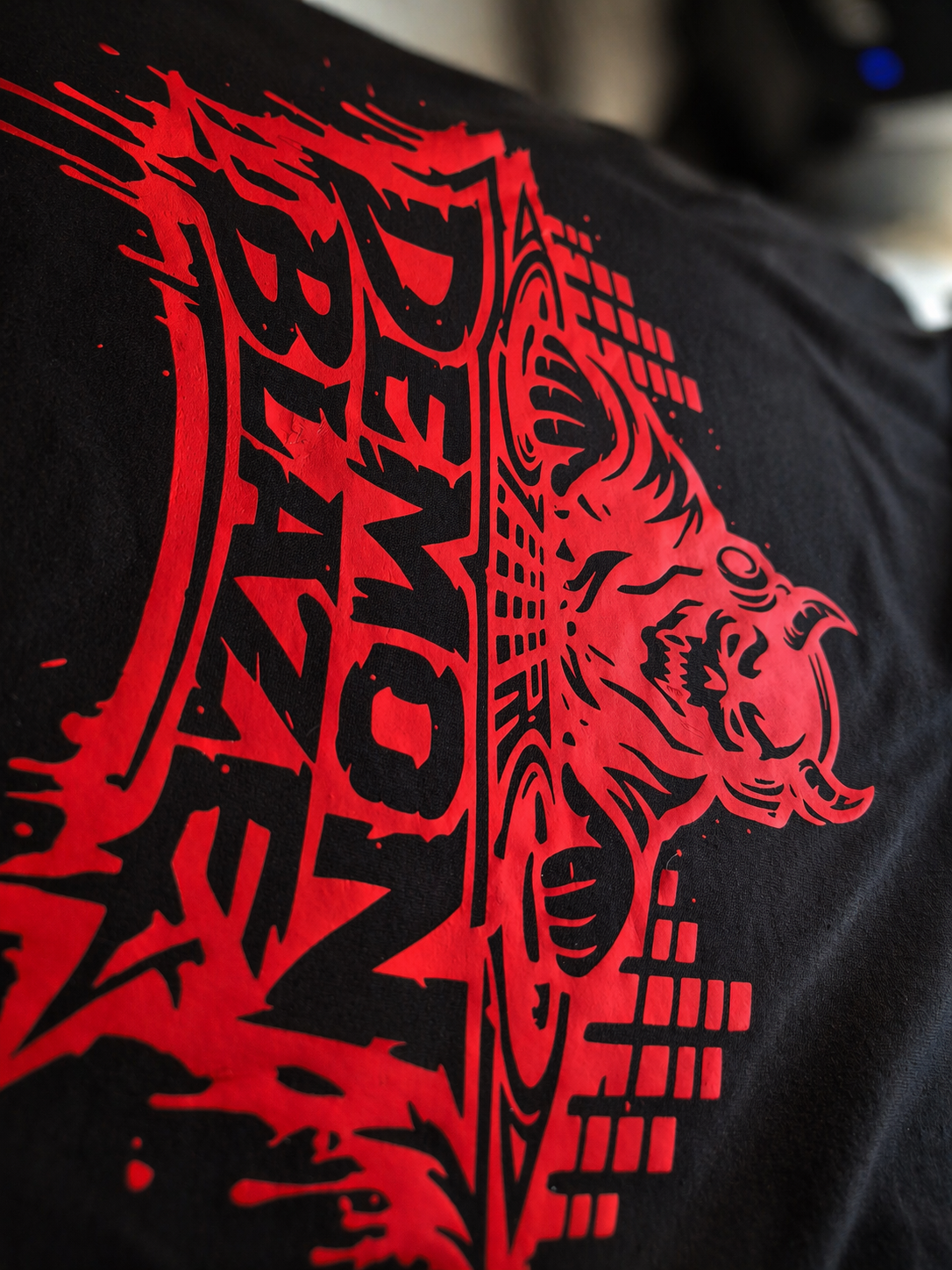 Close-up of a black fabric with a red and black graphic design featuring a stylized creature and the text 'Squad'.