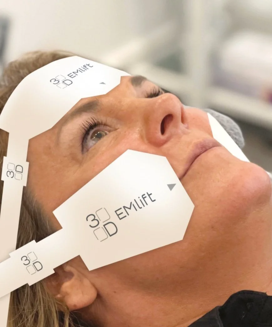 A woman undergoing a facial treatment with a specialized scanning device on her face, in a clinical setting.