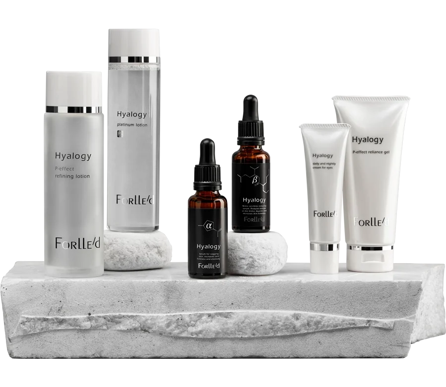 Collection of skincare products, including lotions, serums, and creams, arranged on a white stone platform against a white background.