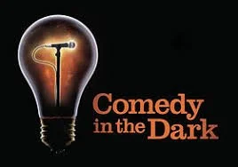 Logo featuring a lightbulb with a microphone inside it and the text 'Comedy in the Dark'.