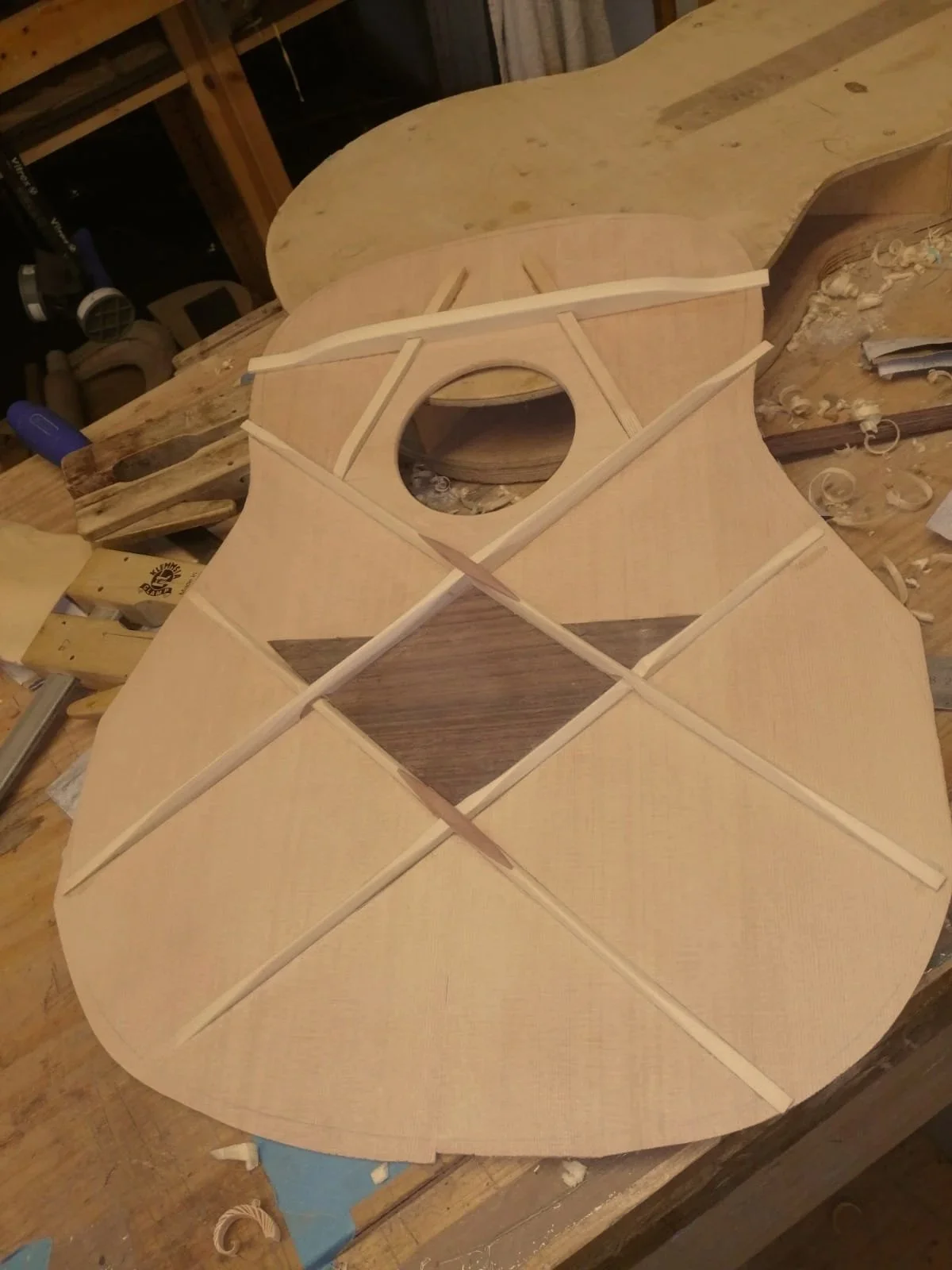 Guitar body in the process of being built, with the top laminate partially attached and internal bracing visible.