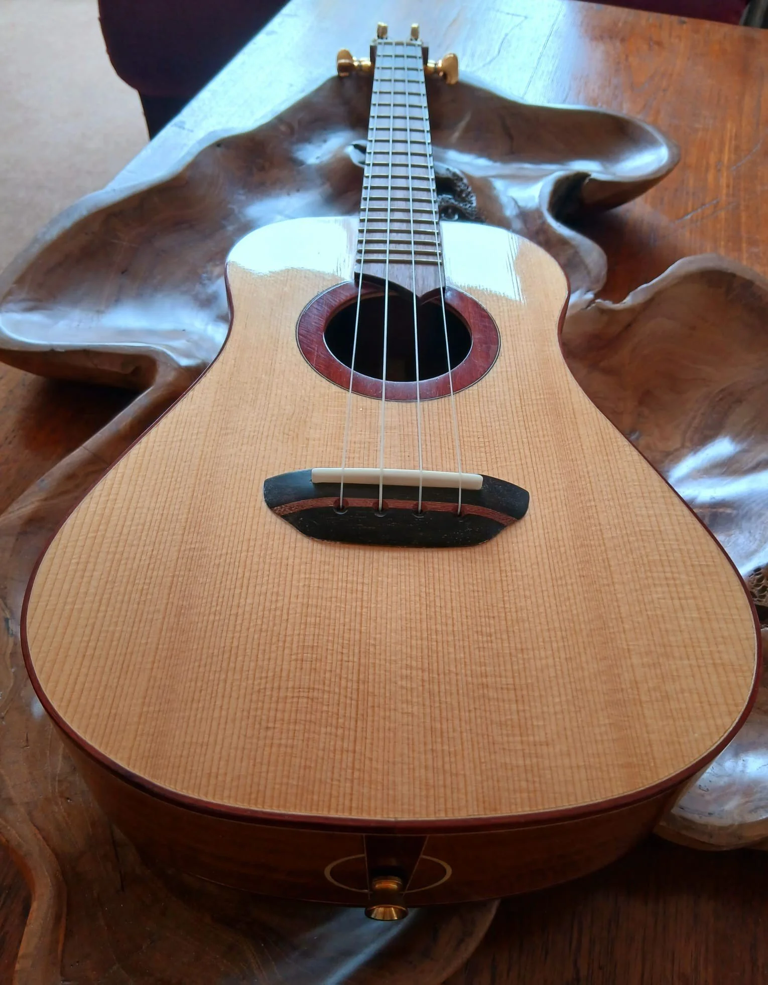 A wooden acoustic guitar lying on a decorative wooden tray on a wooden surface.