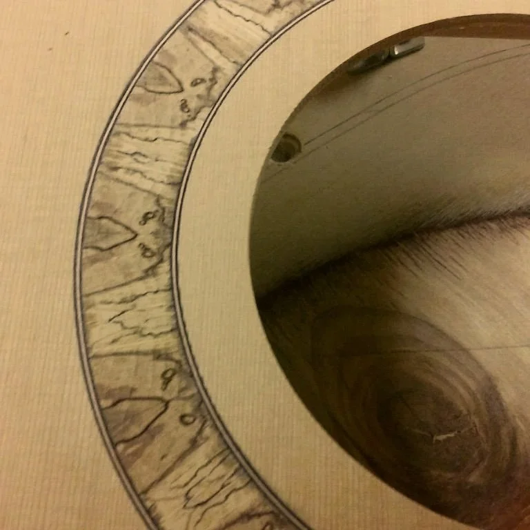 Close-up view of the inside of an acoustic guitar, showing the soundhole and the wood grain of the body.