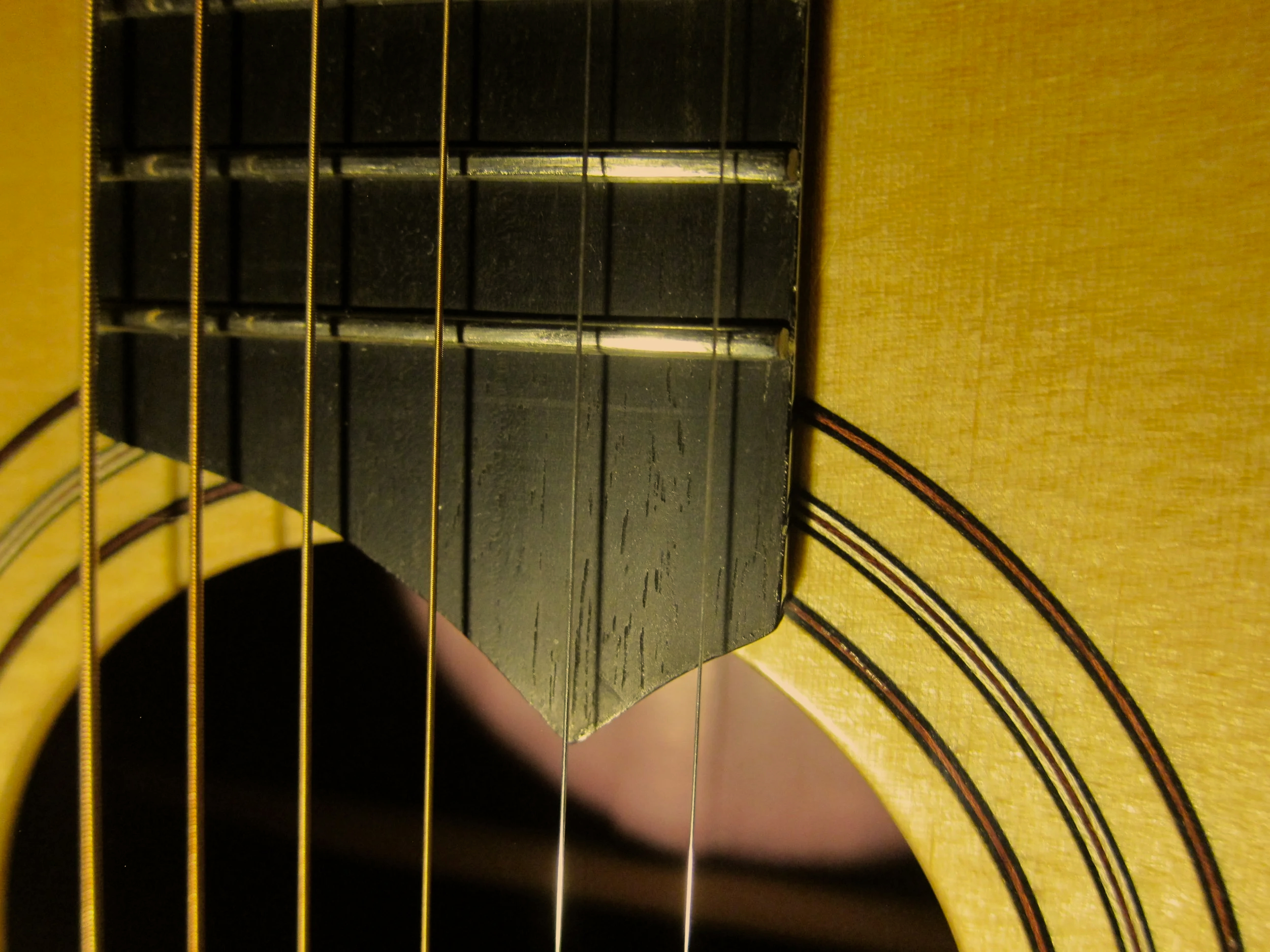 Close-up of a yellow acoustic guitar body and fretboard with metal strings.