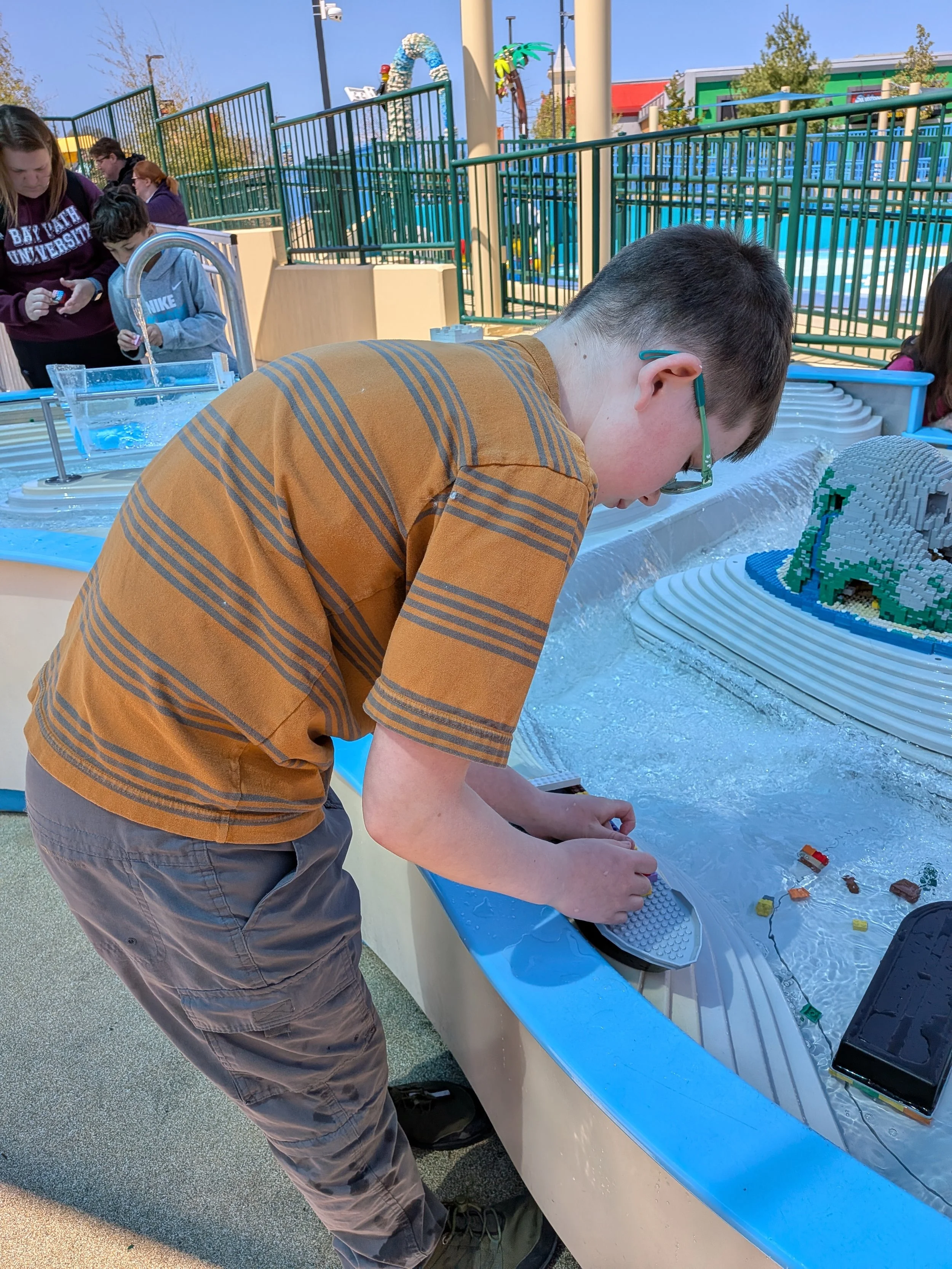 Boy building boat out of LEGO in front of a water table