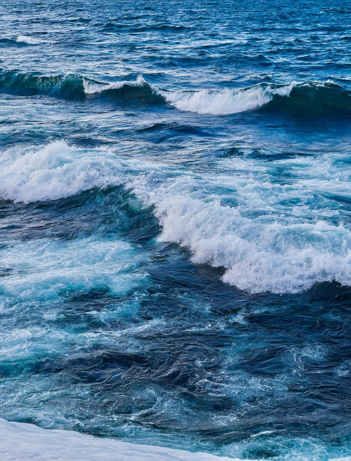 Ocean waves crashing in the sea with blue water and white foam.