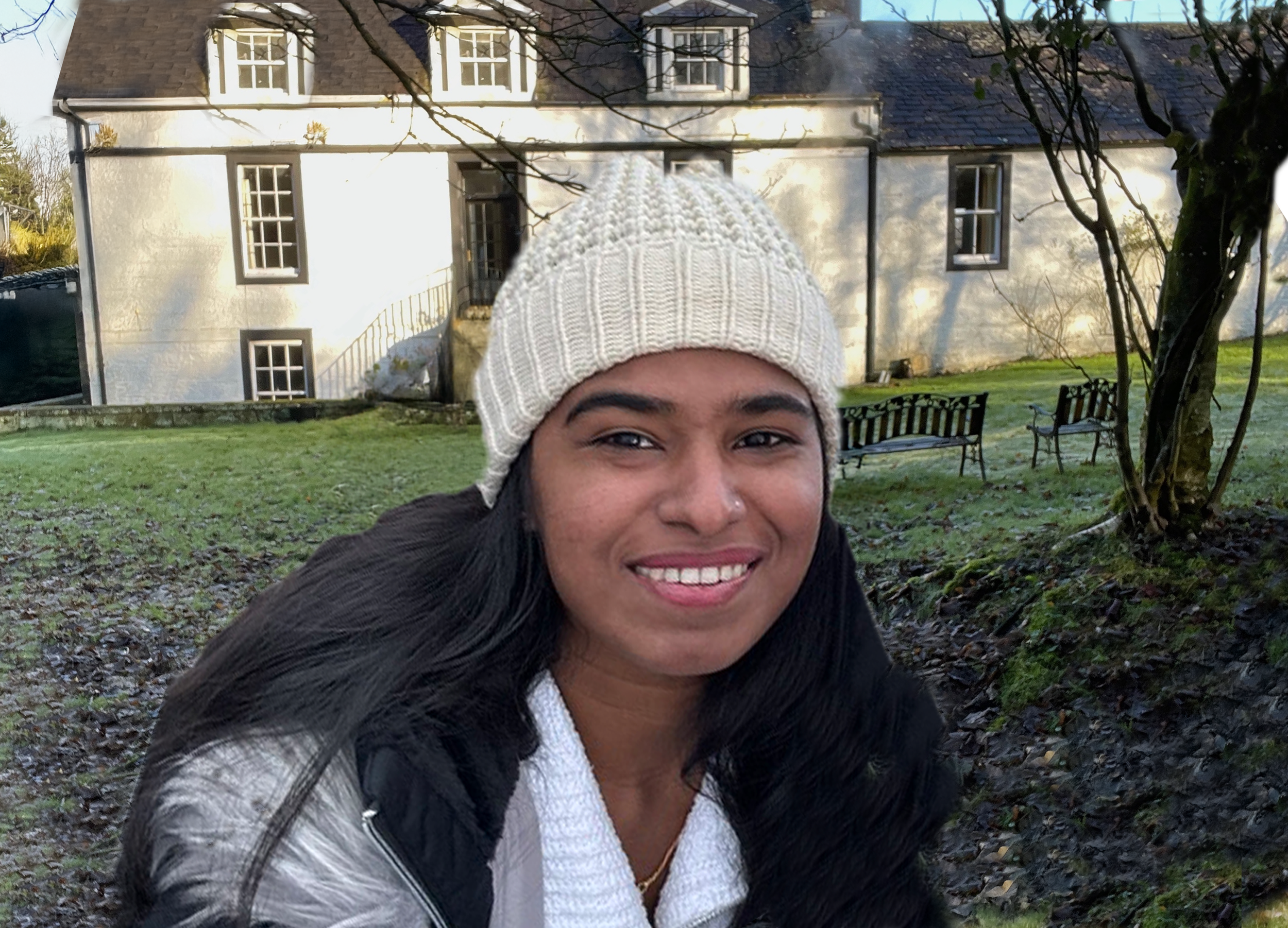 A young woman, wearing a white woollen hat, smiling broadly