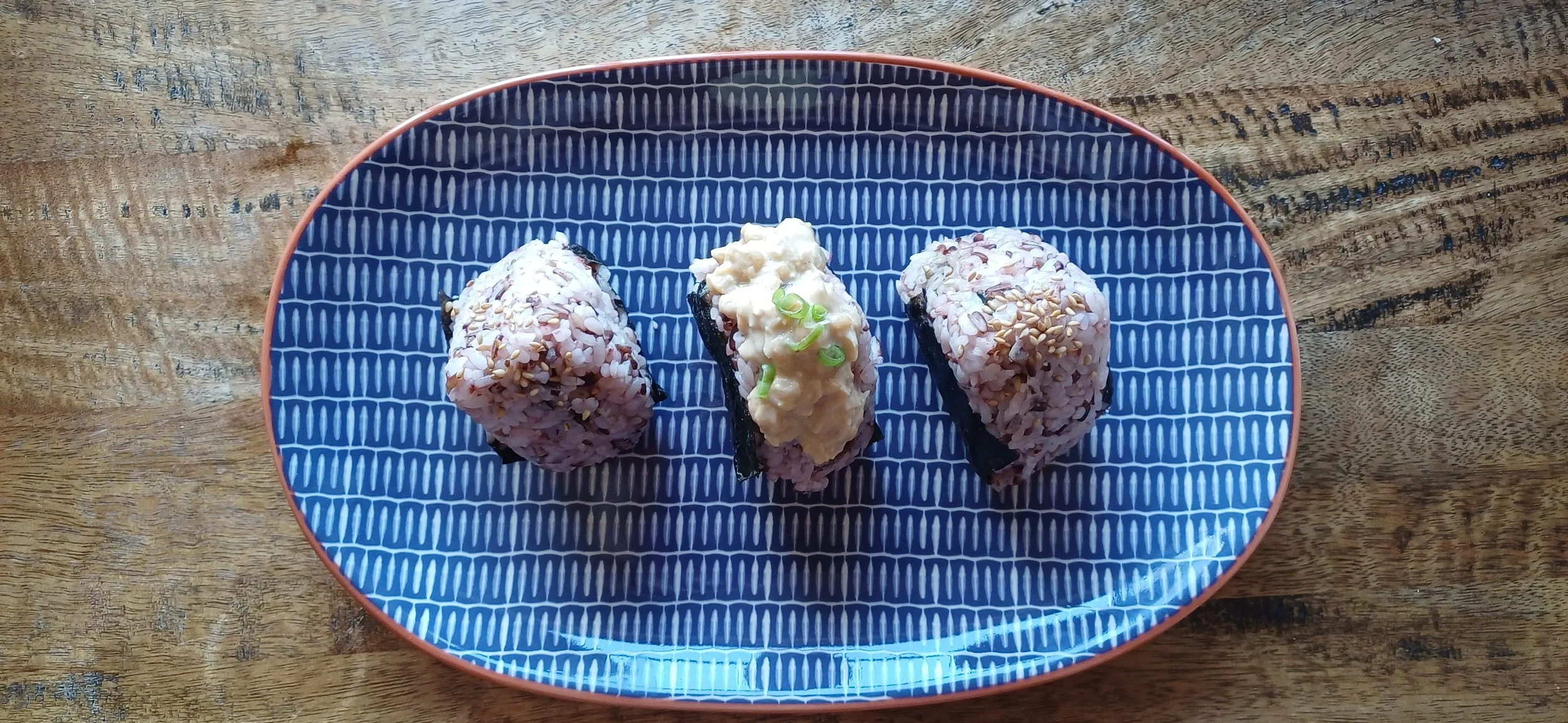 Japanese ongiri rice balls with seasonal plant-based fillings, served on a blue ceramic plate