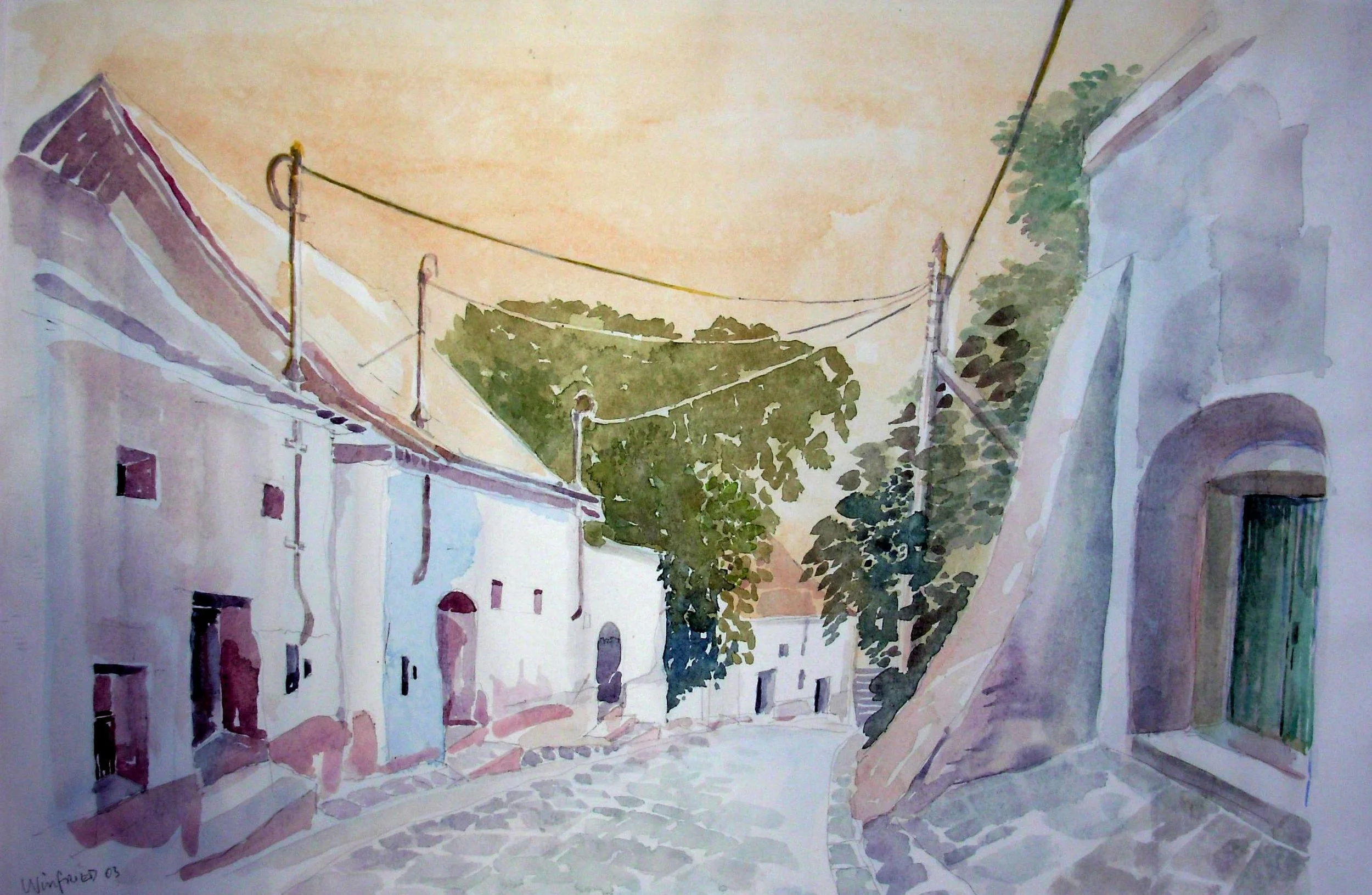 A watercolor painting of a quiet cobblestone street in a small village with white buildings, green trees, and power lines, during sunset.