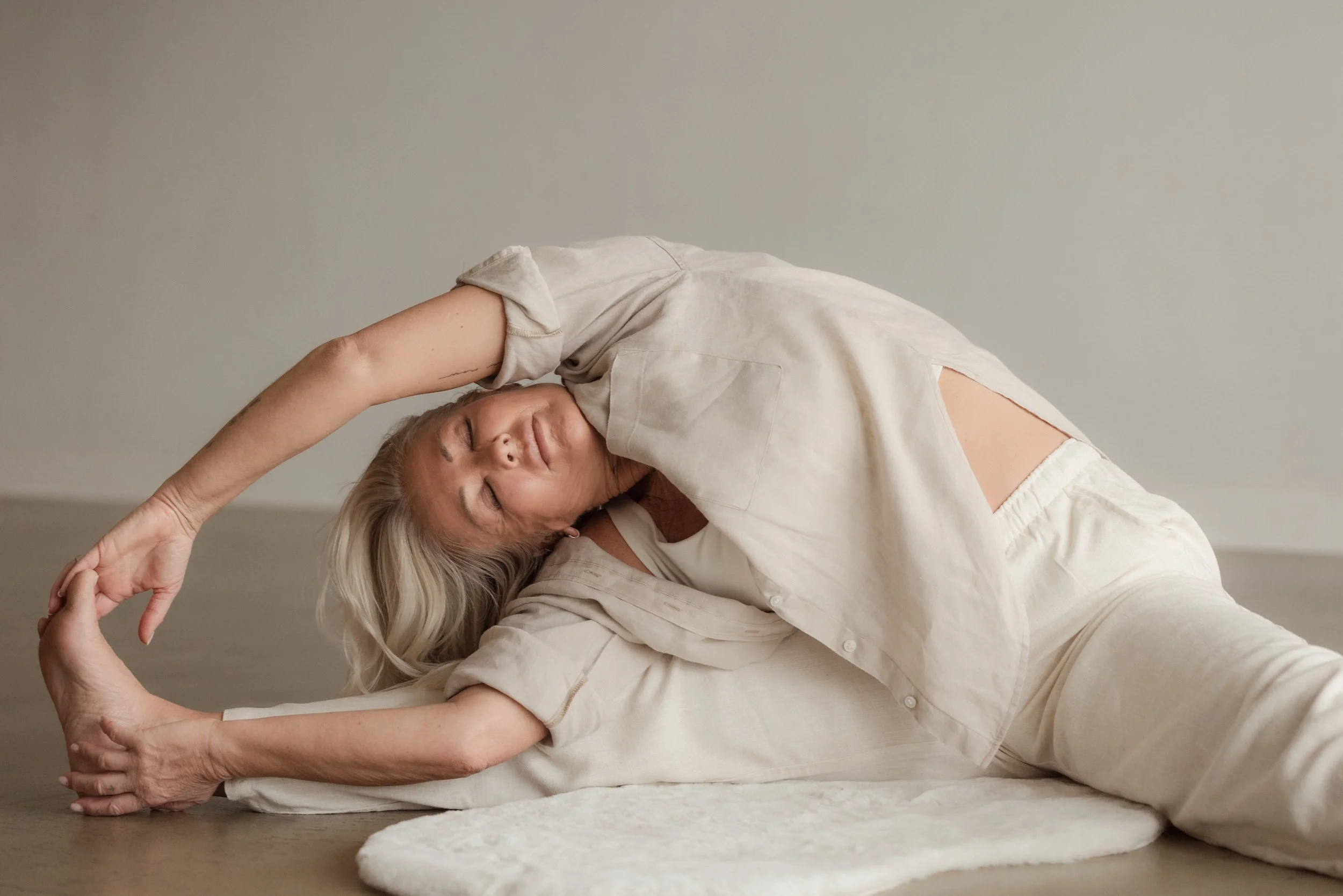 A woman with blonde hair performing a floor stretch exercise.