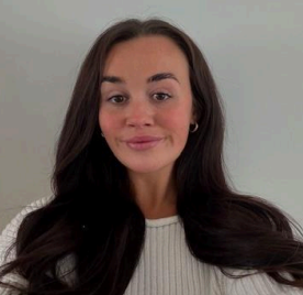 A young woman with long dark hair, wearing a white knit sweater, smiling at the camera against a plain light gray background.