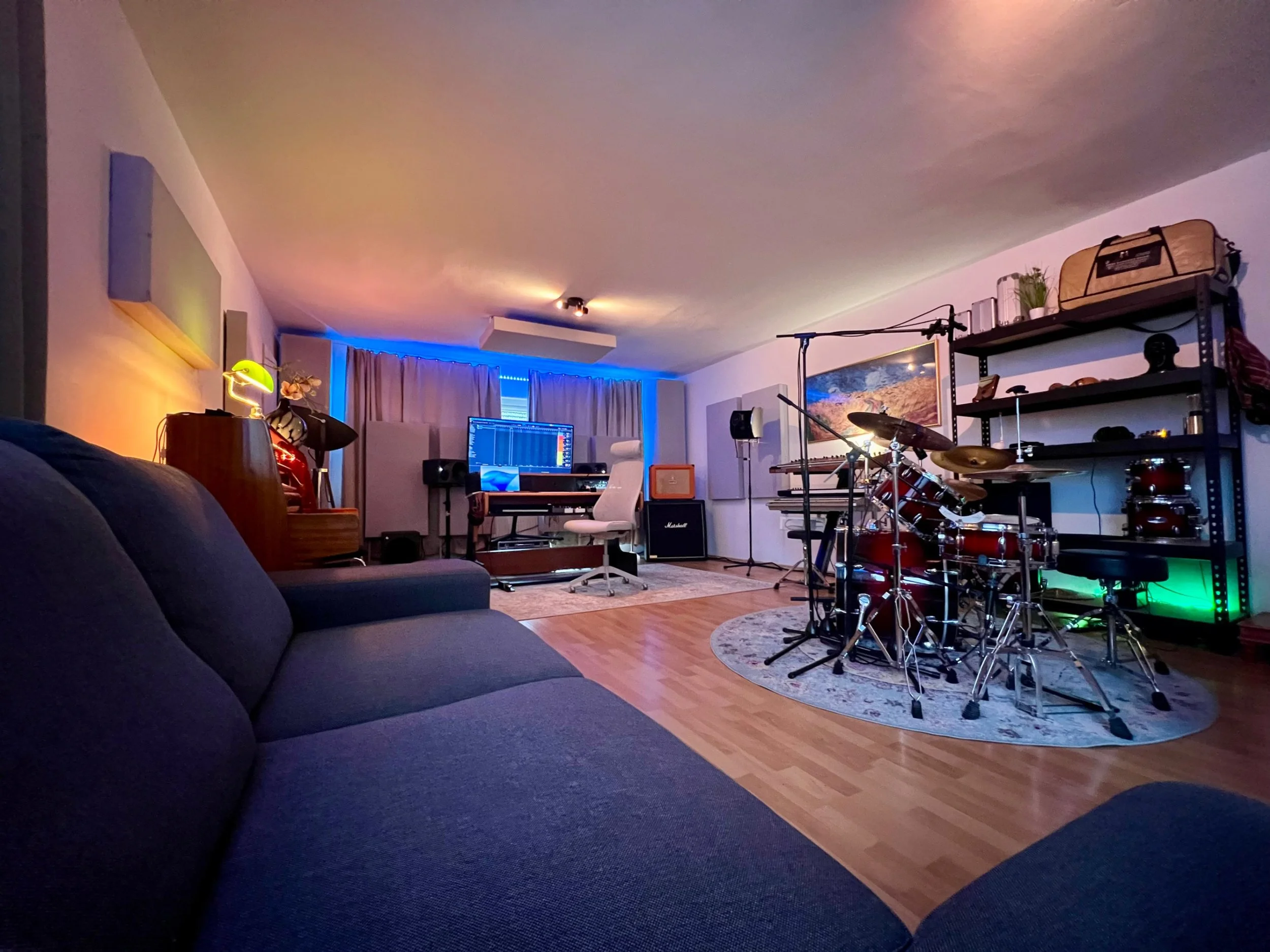Ein Wohnzimmer mit Musikinstrumenten, einem Computer, einem Sofa und Dekorationen in warmem Licht, mit blauen Lichteffekten im Hintergrund.