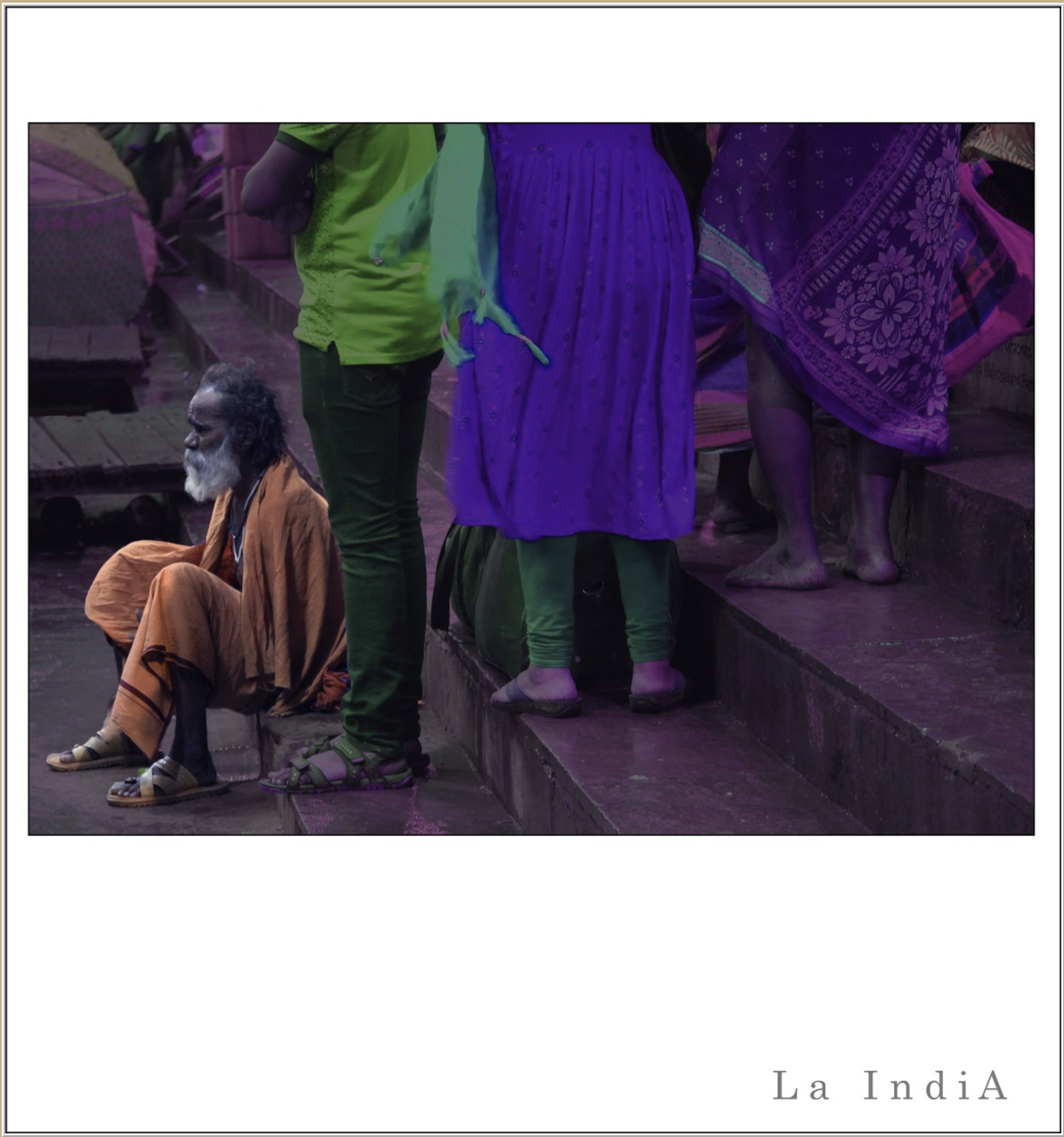 People standing in a market with some wearing traditional Indian clothing, and an elderly man sitting on the ground. There are textiles and goods visible in the background.