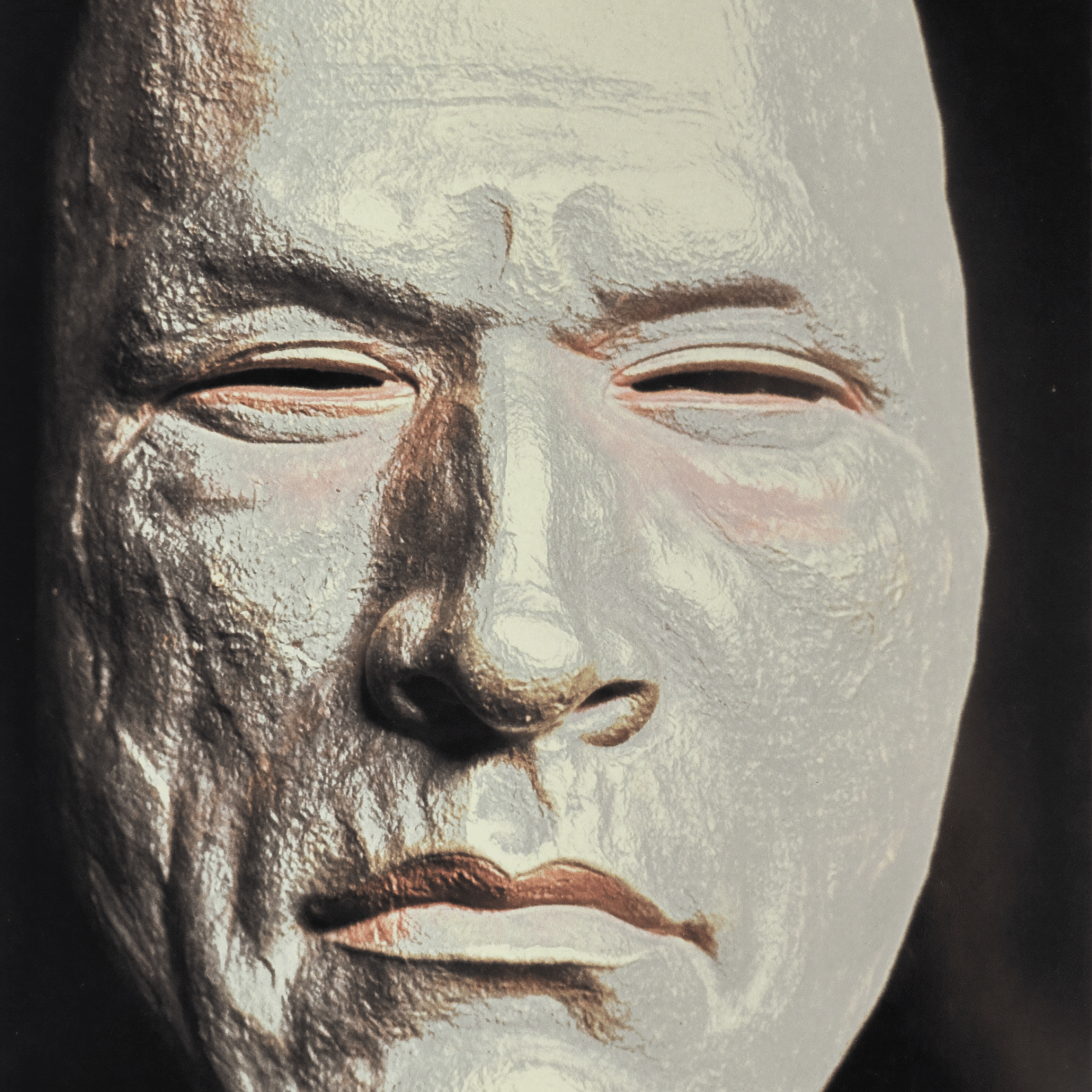 Close-up of a metallic mask with a smooth surface, highlighting the eye area and part of the nose, with a textured finish.