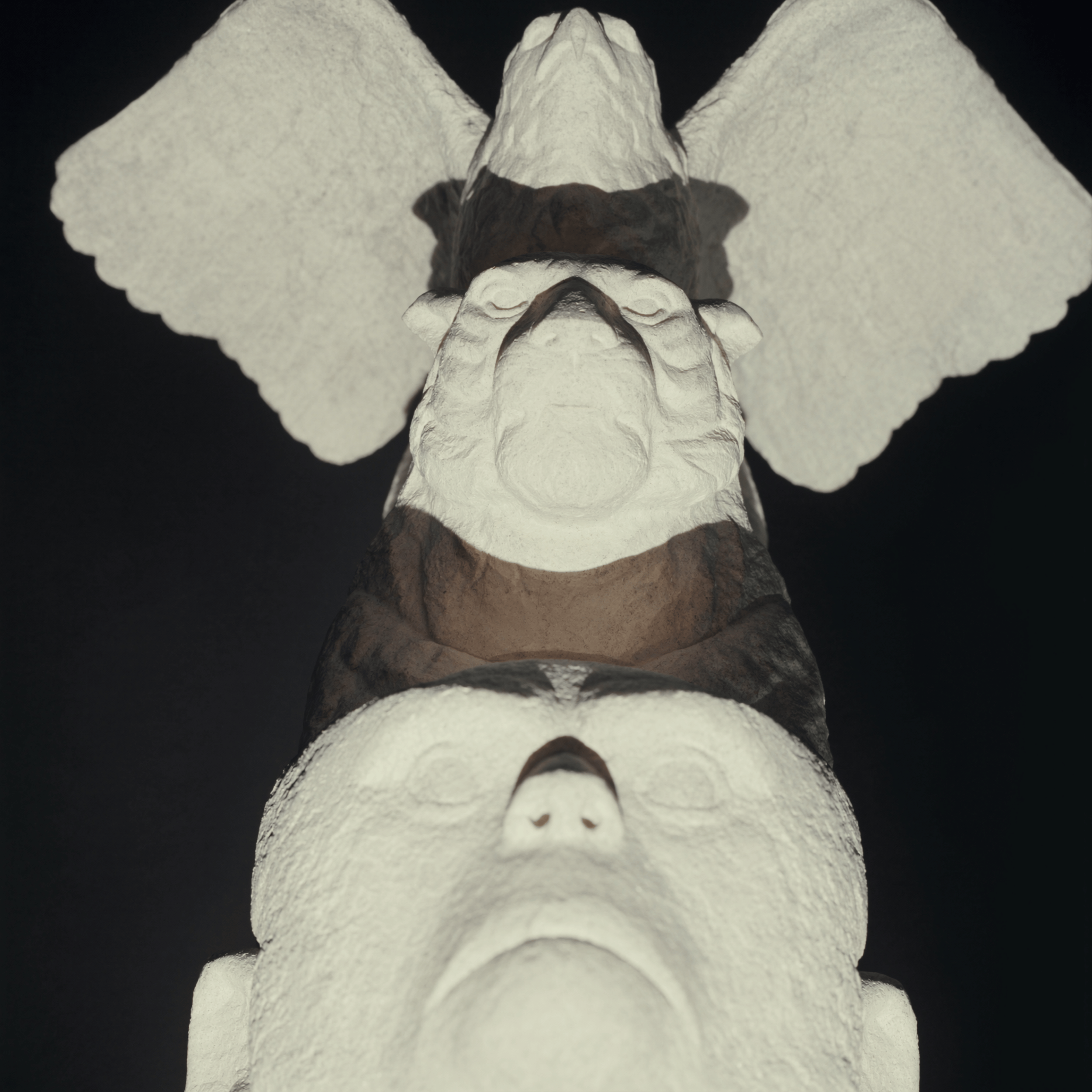 A symmetrical, black and white, abstract sculpture resembling a face with prominent, curved features and textured surface.