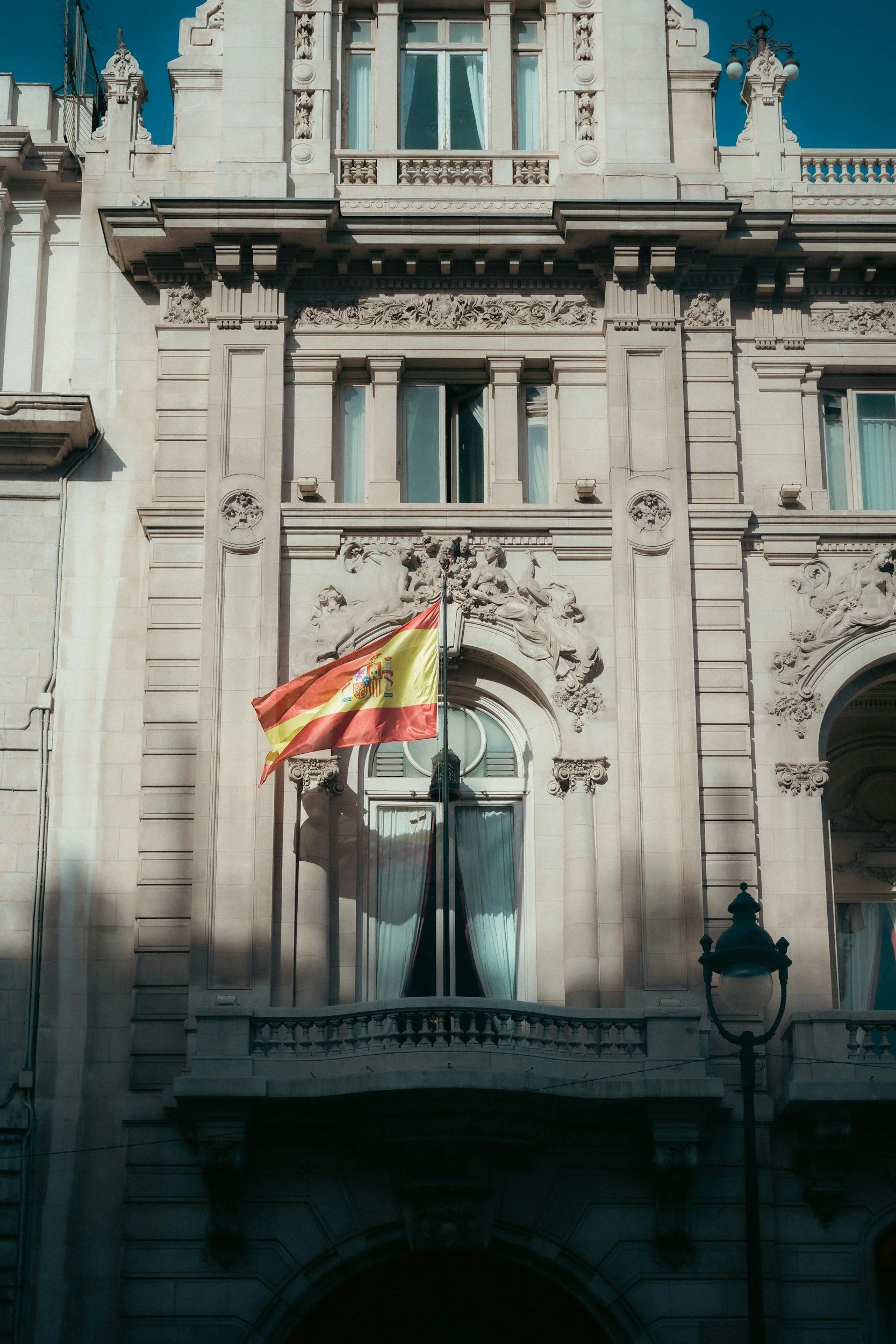 Edificio histórico con detalles ornamentales y bandera de España en un balcón