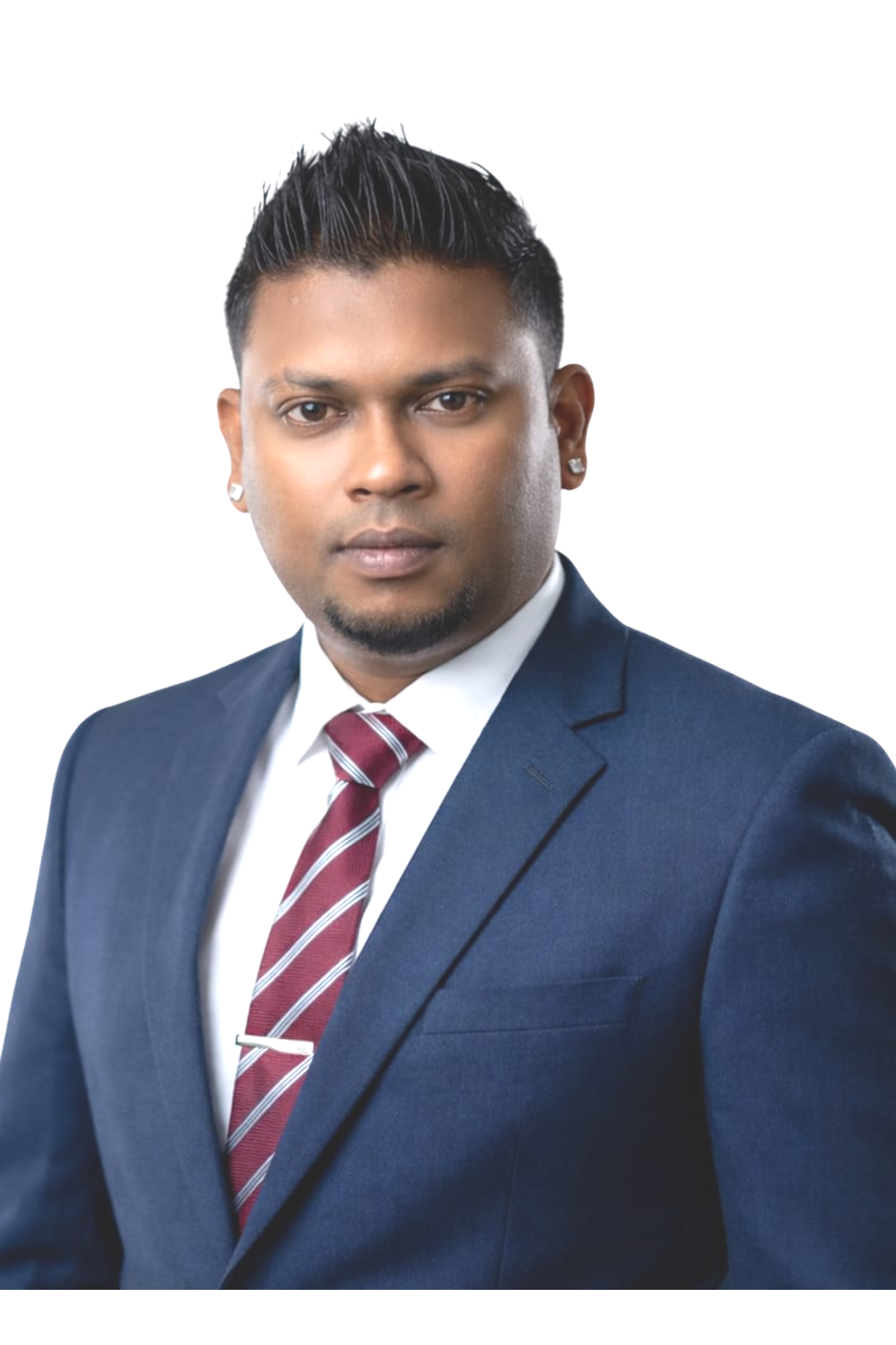 Professional portrait of a man in a dark blue suit, white shirt, and red striped tie, with short spiked hair and earrings, against a white background.