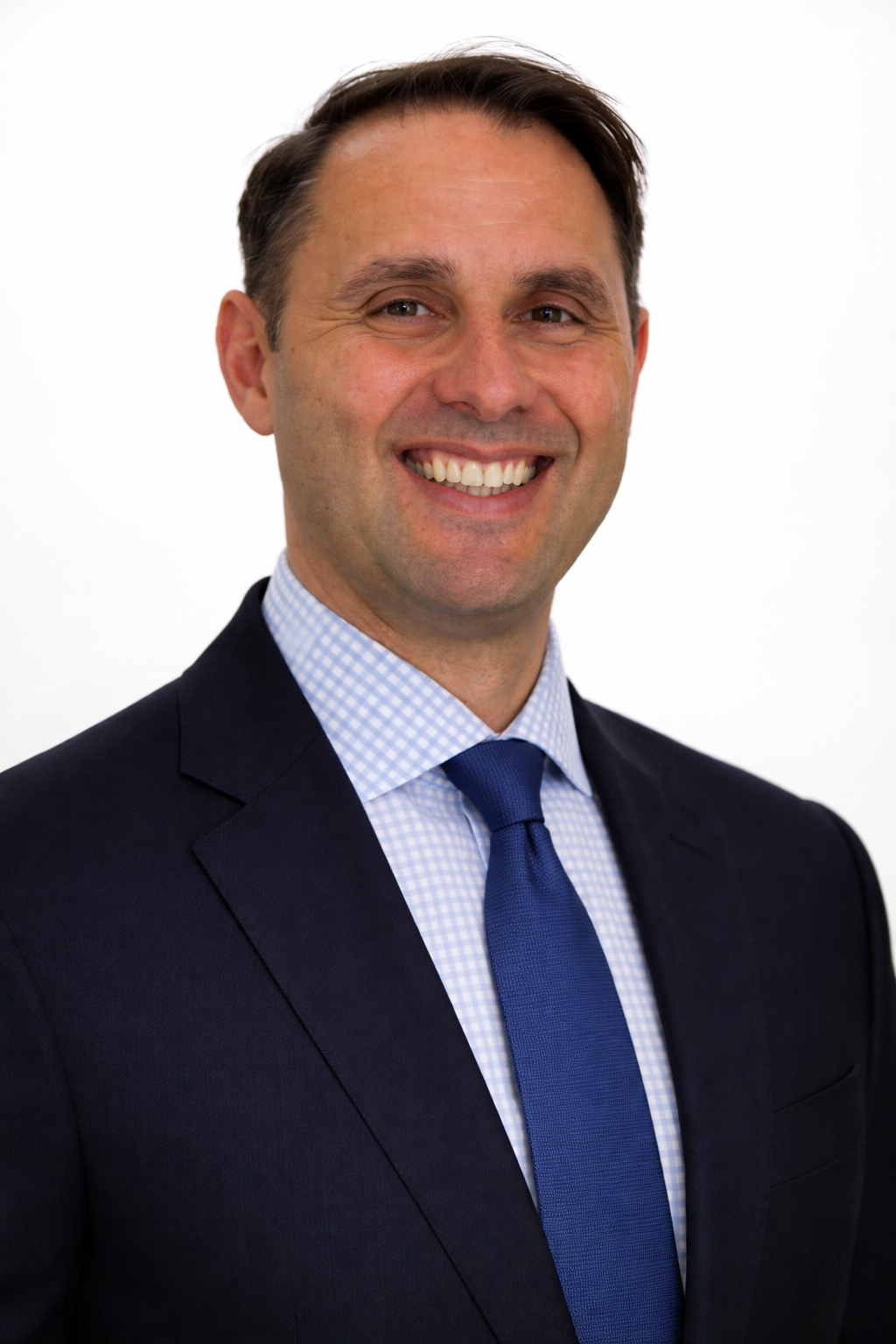 A man in a suit smiling against a white background.