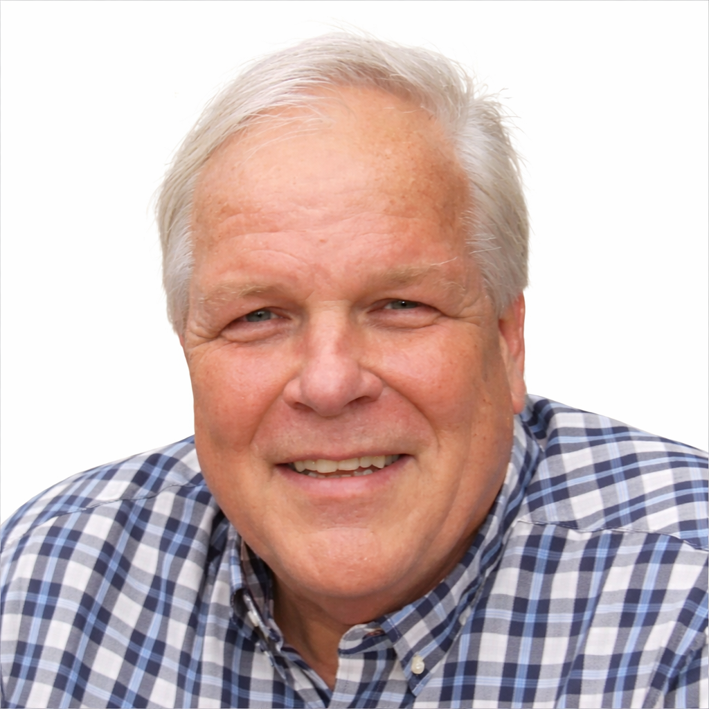 A smiling older man with white hair wearing a blue and white plaid shirt.