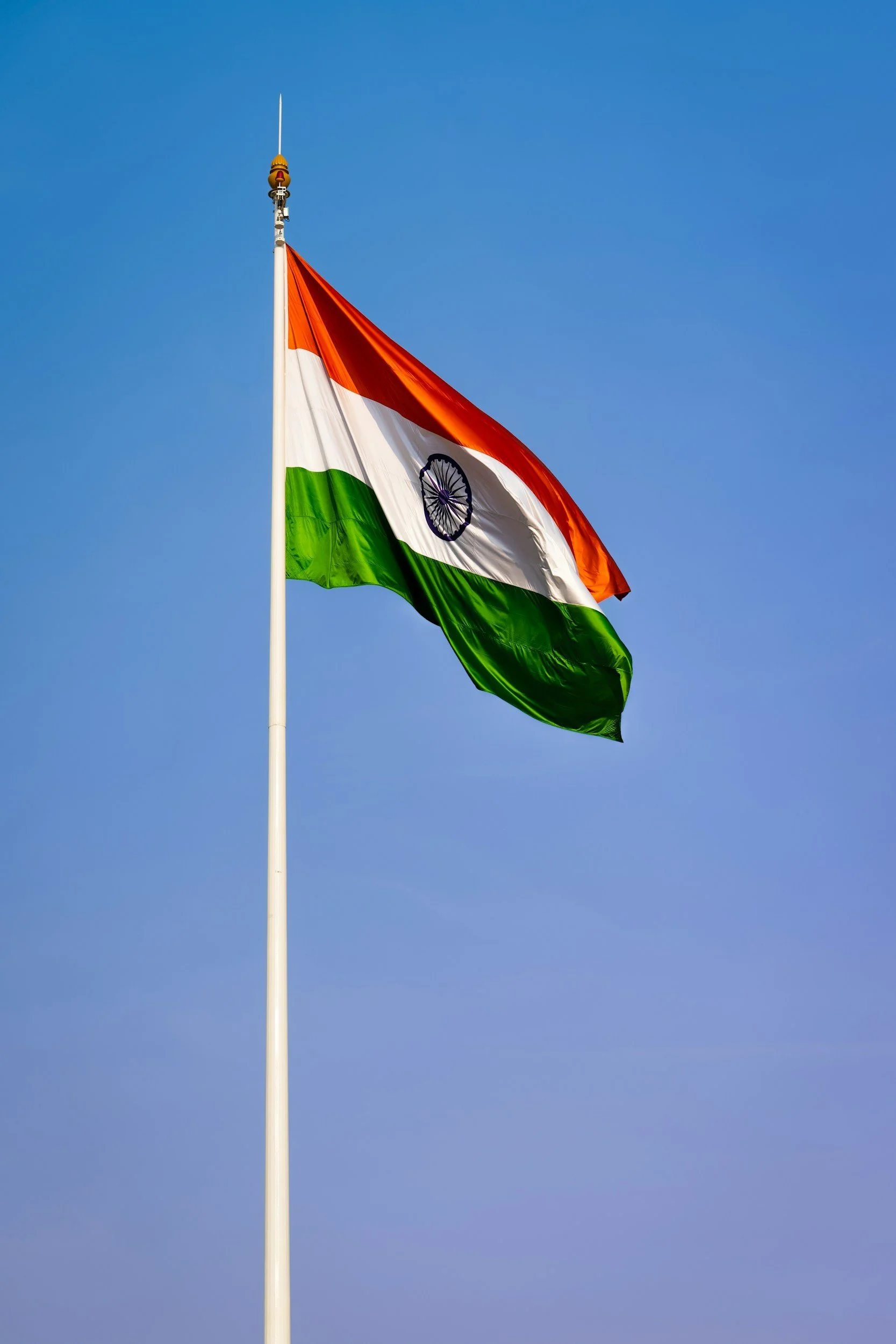 Indian national flag flying against a clear blue sky.