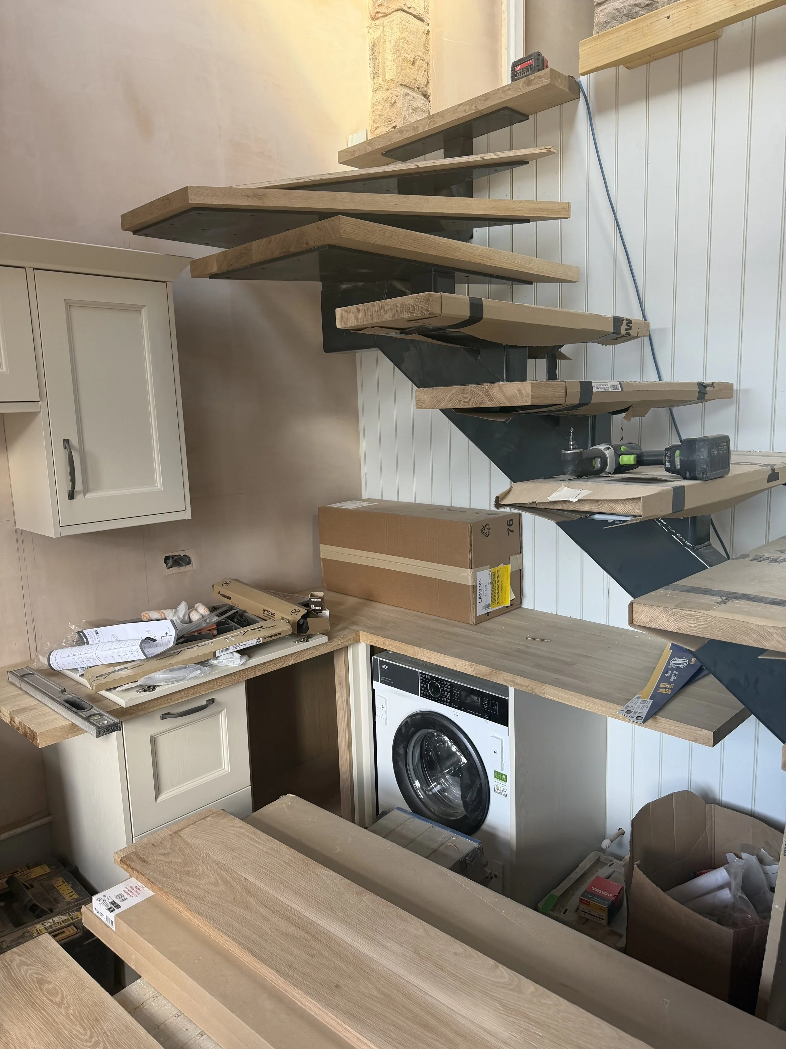 Interior of a kitchen under construction with wooden countertops, an oven, and various tools and boxes around.