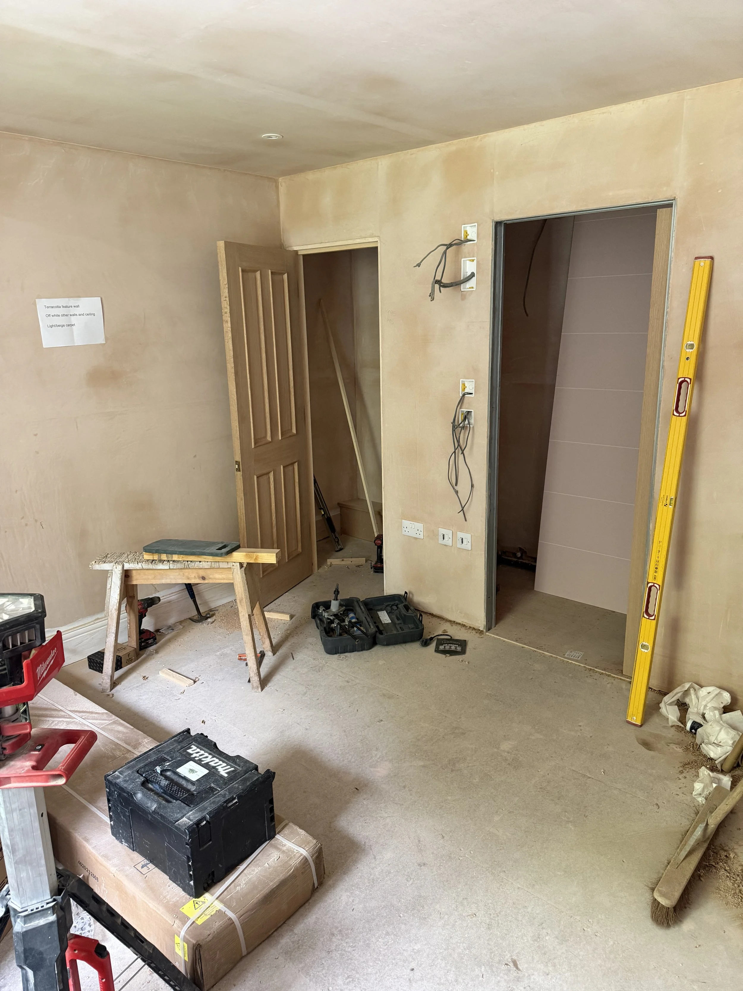 Room under construction or renovation with tools, a level, a broom, and wired outlets.
