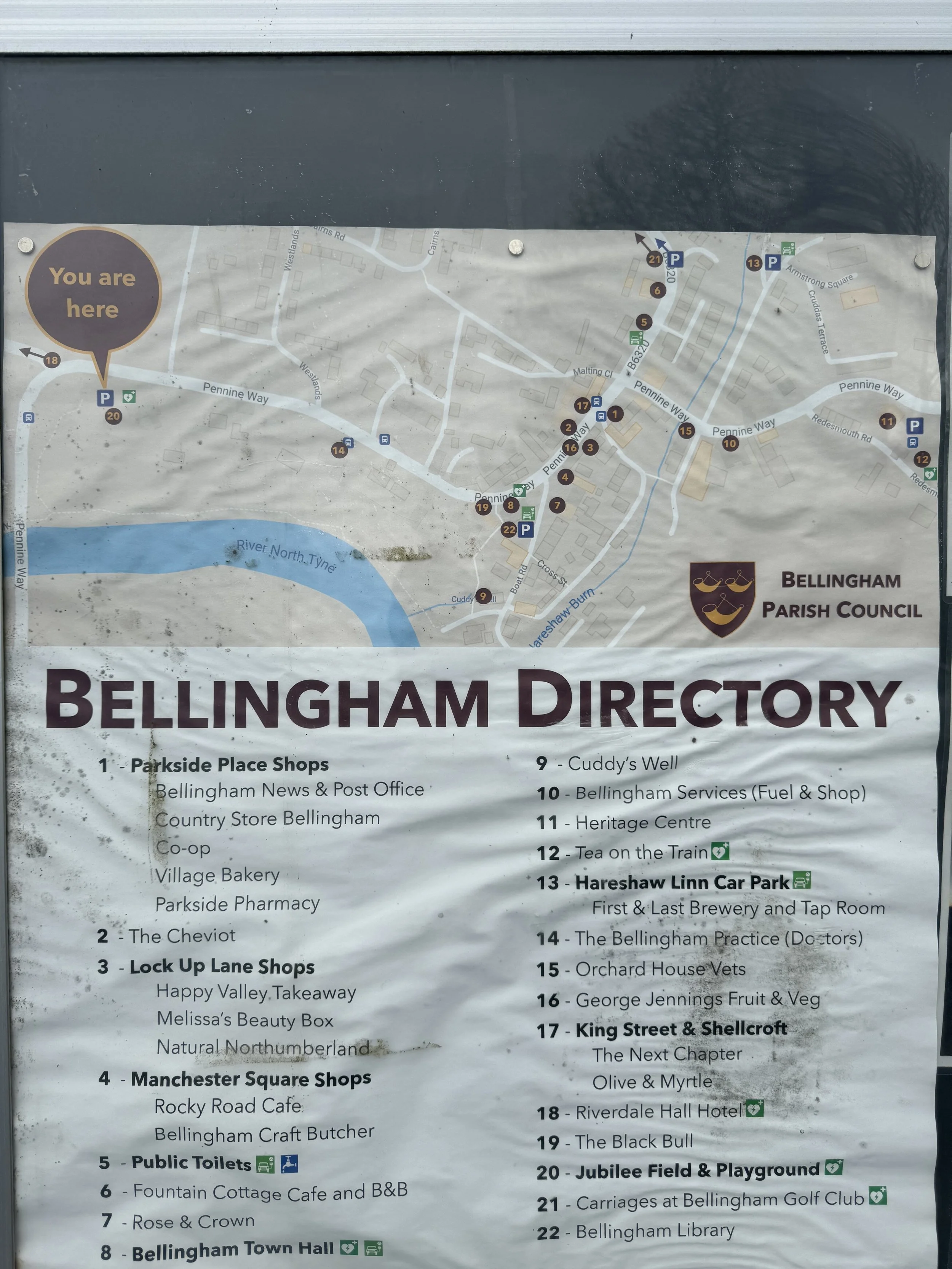 Map of Bellingham with numbered locations and a legend listing shops, services, and landmarks in the area, including parks, shops, public toilets, cafes, a town hall, and other community facilities.