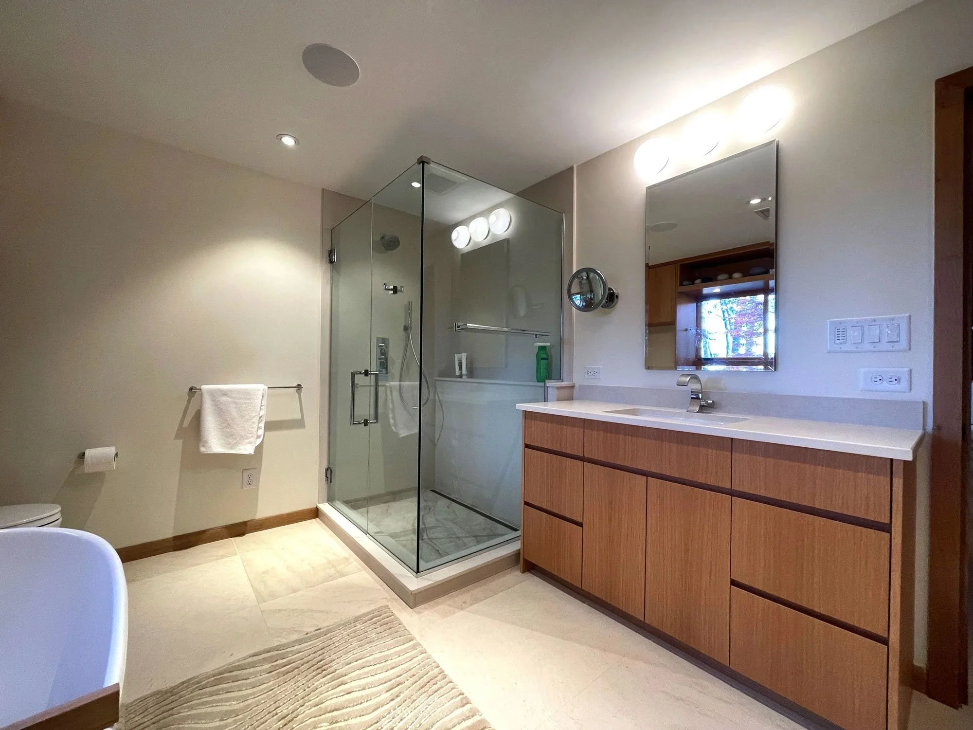 A modern basement guest bathroom with a glass walk-in shower enclosure.
