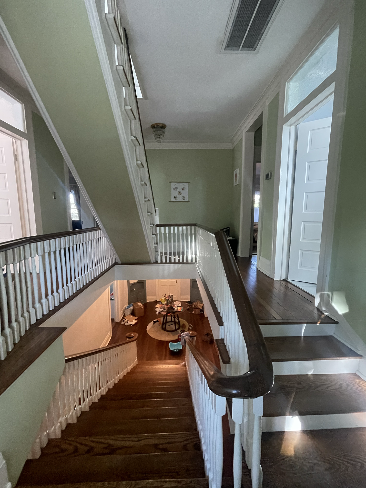 A multi-story interior staircase with green walls, white railings, and dark hardwood stairs after Lead Repair, Restoration and Painting.