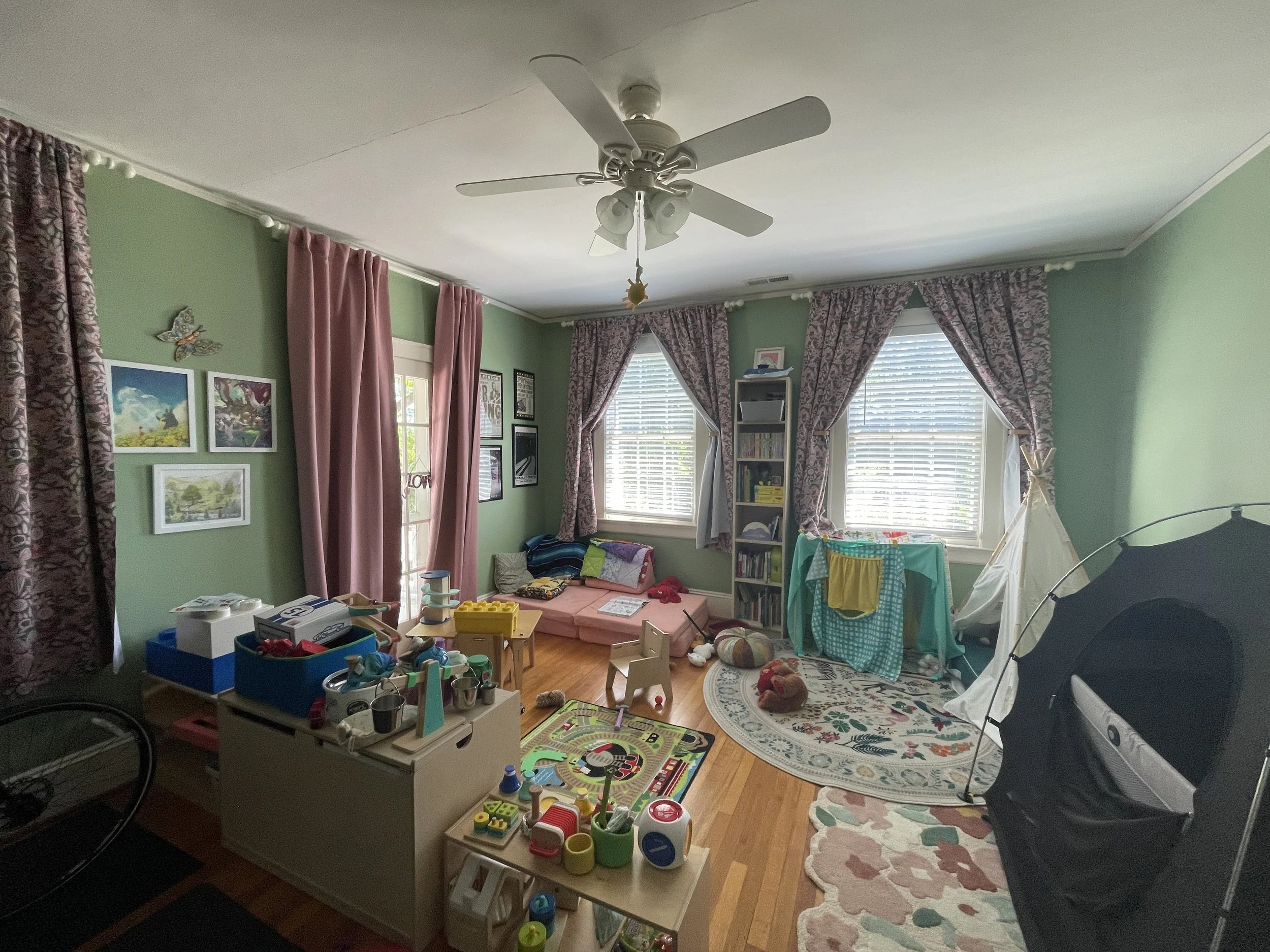 A lived-in children's playroom with green walls, windows with floral curtains. A safe eco room after Lead Repair, Restoration and Painting.