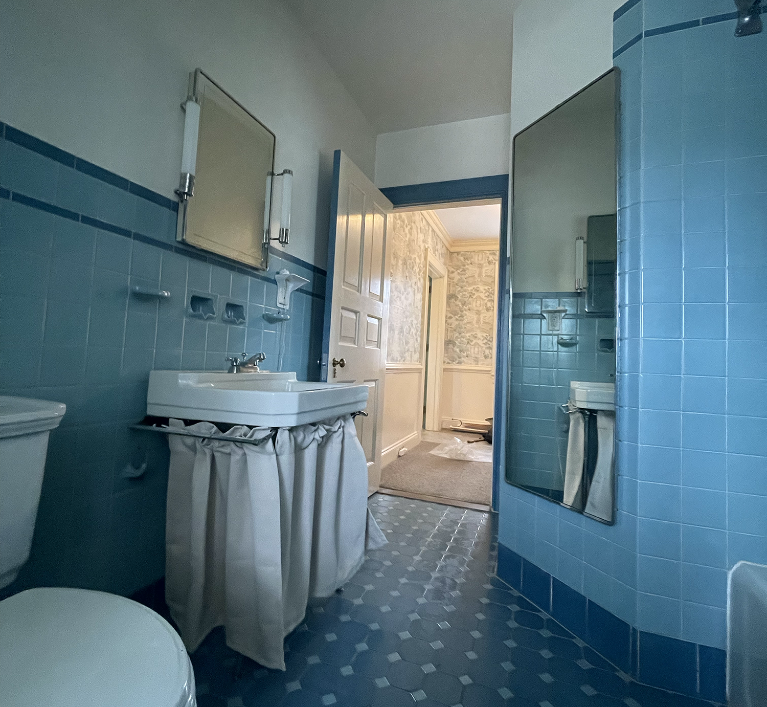 Durham 1950's vintage blue-tiled bathroom with a period white sink to match. After wallpaper removal, the trim, window and door was styled to match the tile.