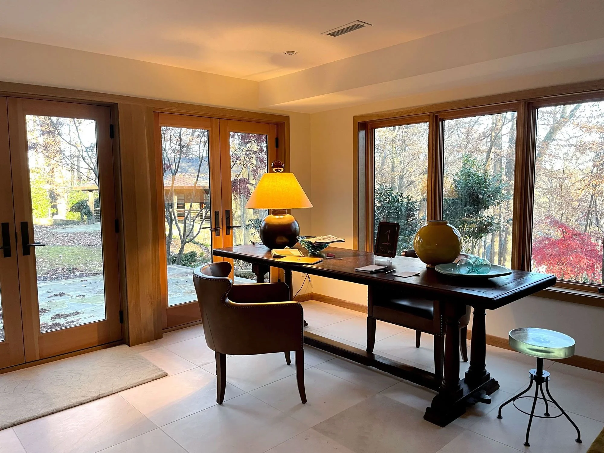 Basement office room with large windows and glass door showing an outdoor view of trees while you work.