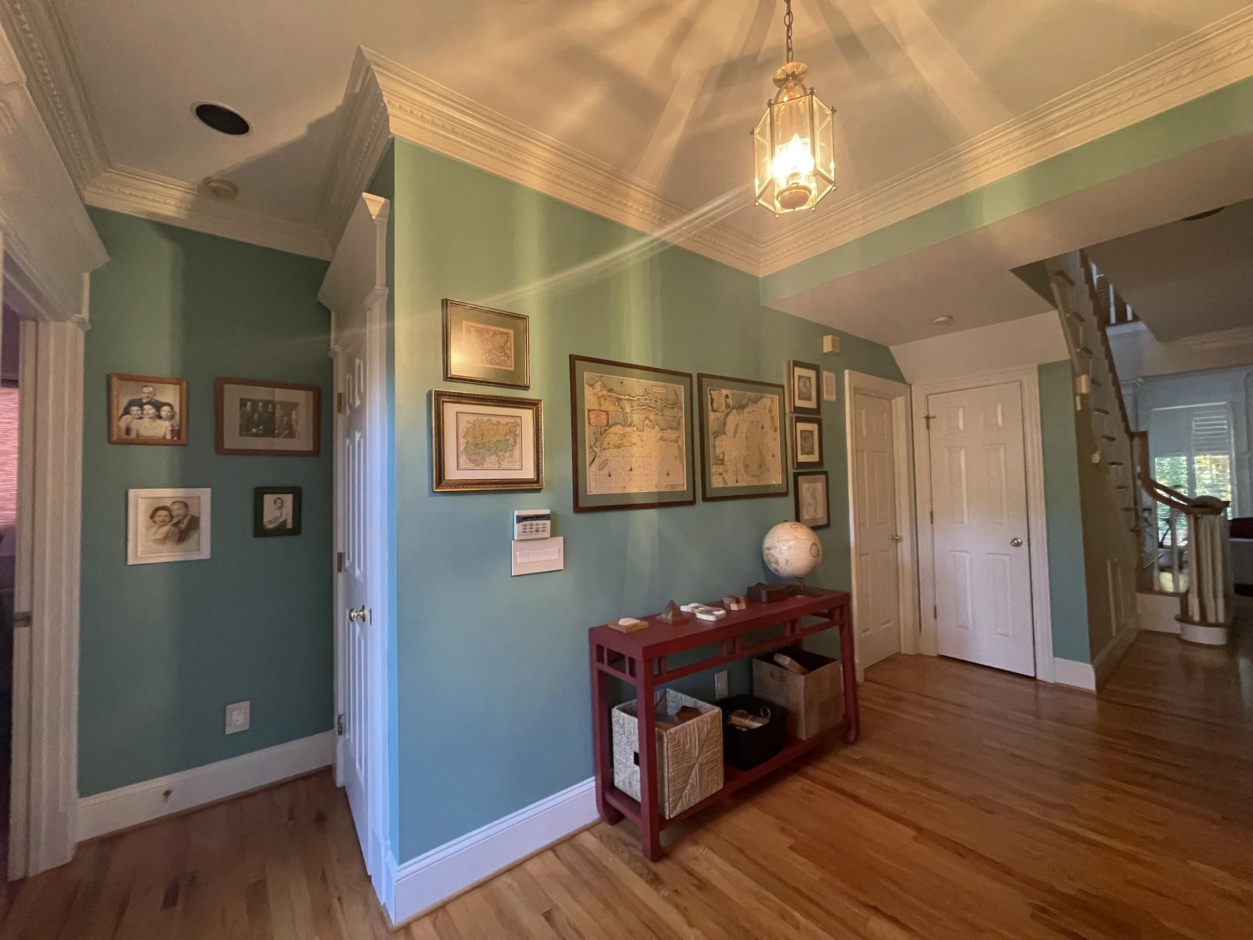 A hallway with light green walls, adorned with framed maps, a globe and photographs says everything about your interests.