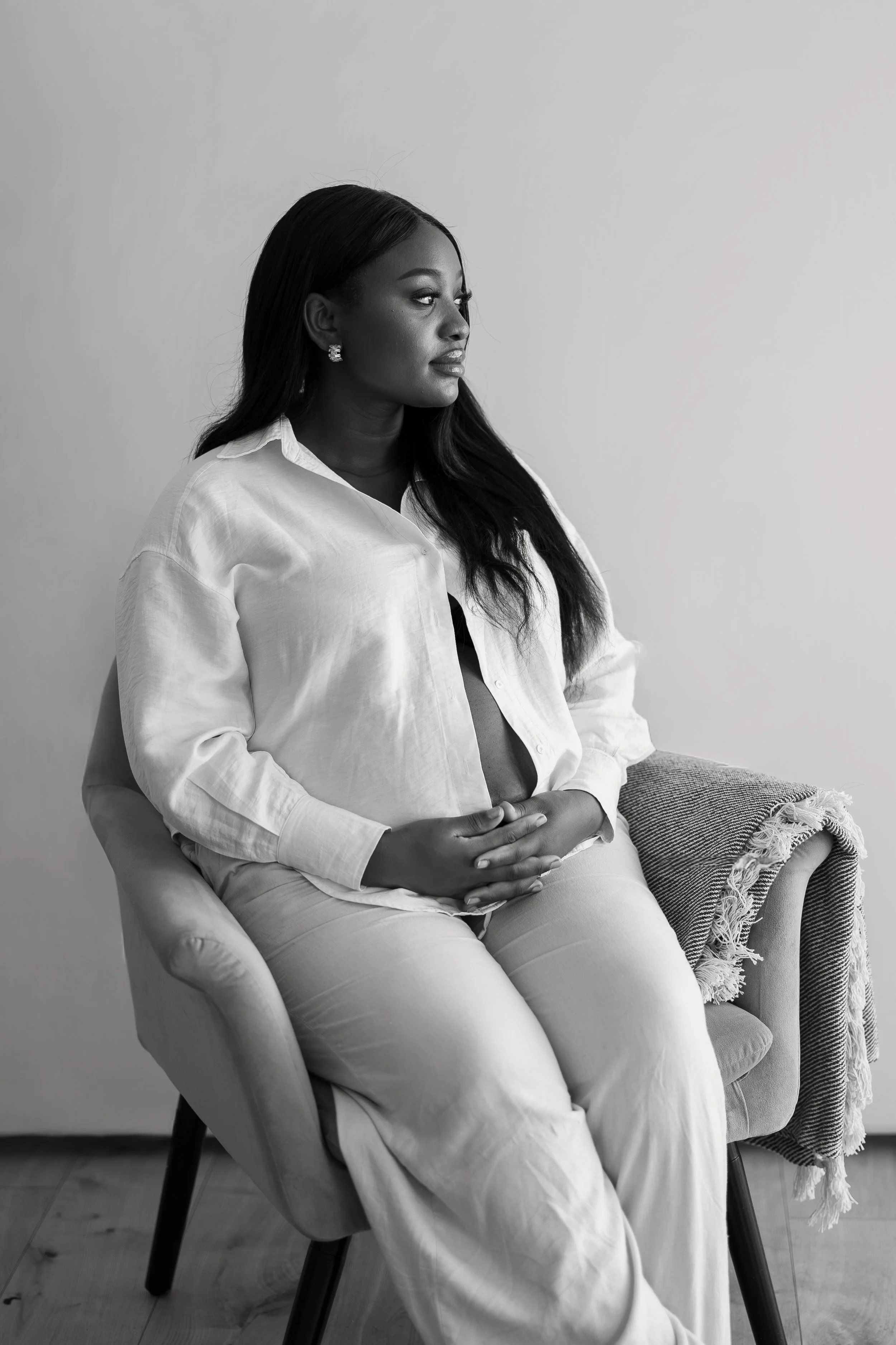 Black-and-white maternity portrait of a seated pregnant woman during a studio session in Adelaide.