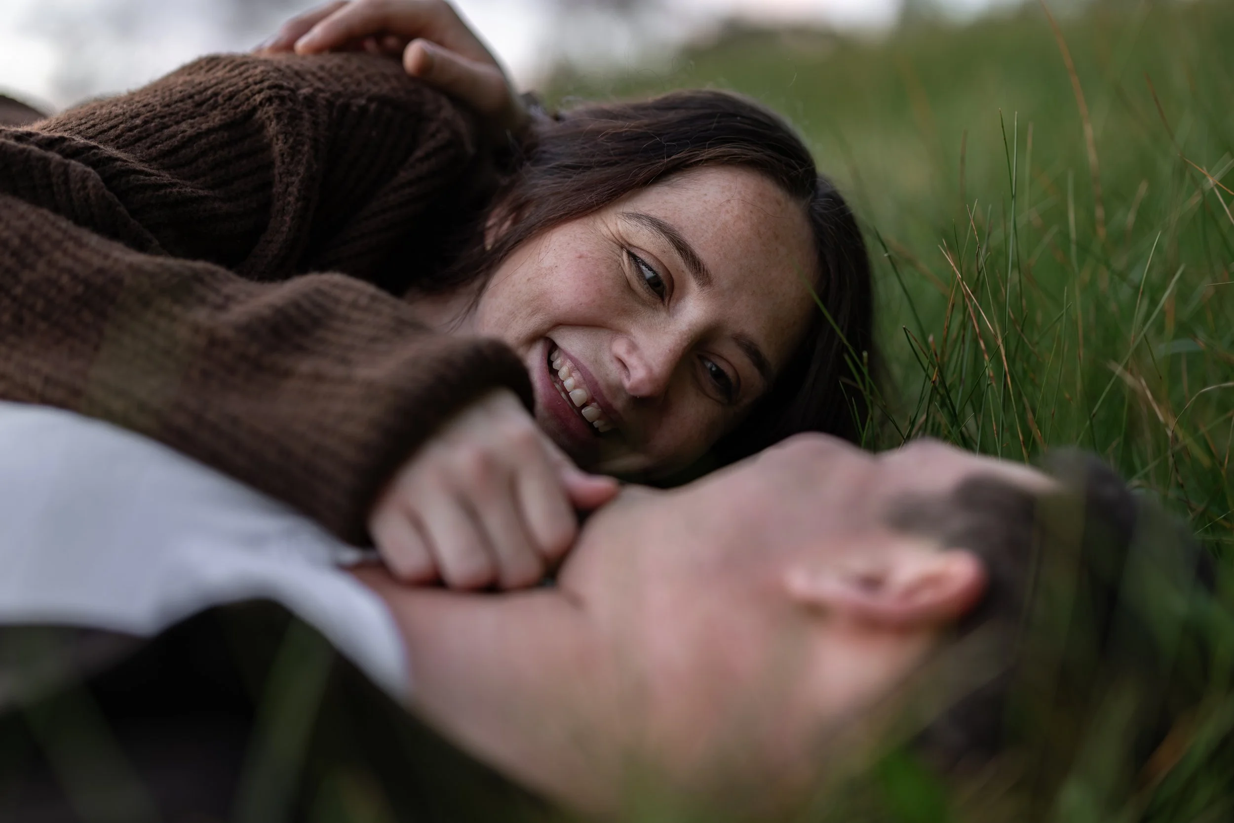 Playful close-up portrait of a couple lying in grass during a couples photography session in Adelaide.