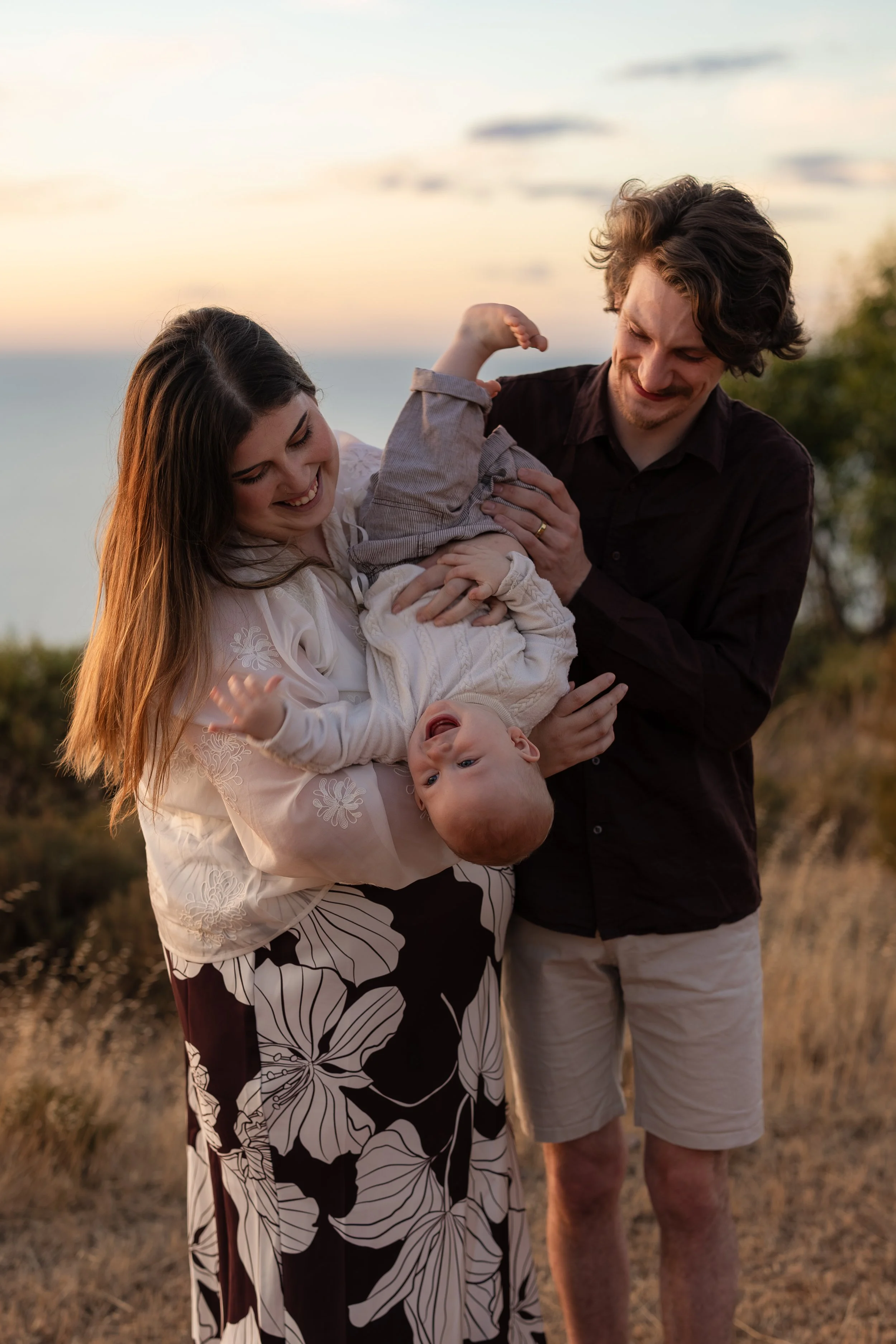 Parents lifting their baby during a family photography session at sunset in Adelaide.