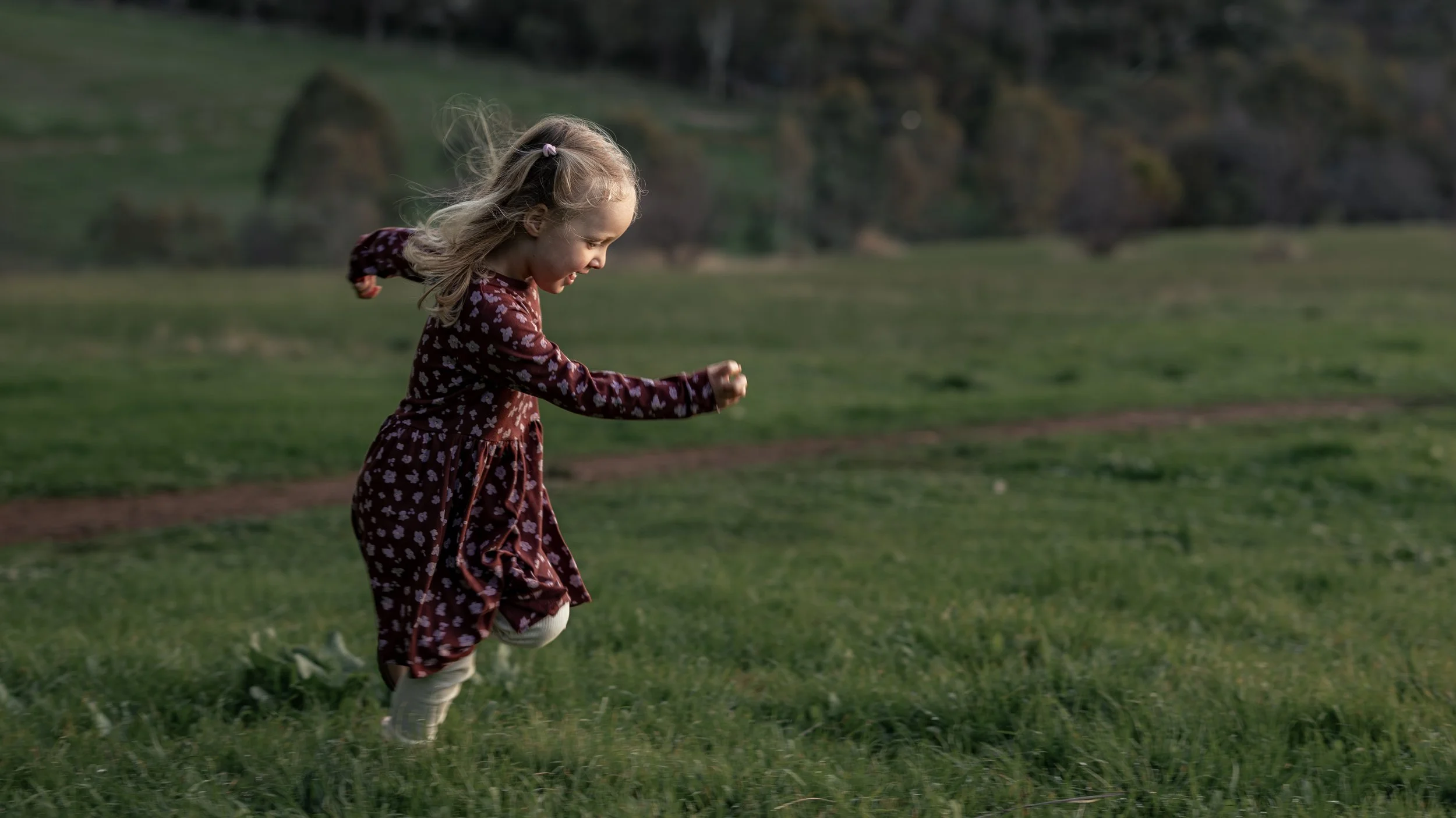 Young child running through an open field during a family photography session in Adelaide.
