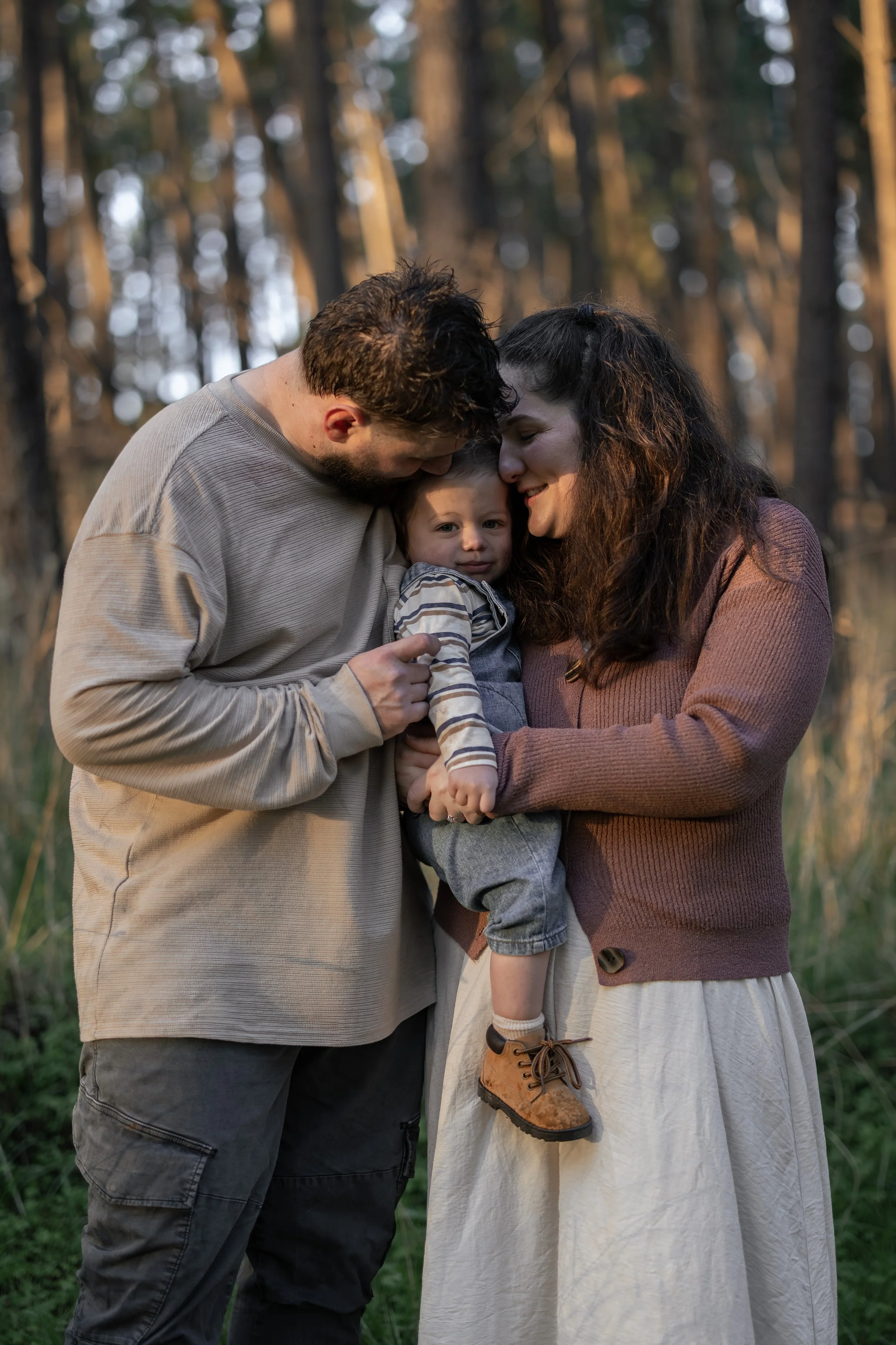 Parents cuddling their baby in a forest during a family photography session in Adelaide.