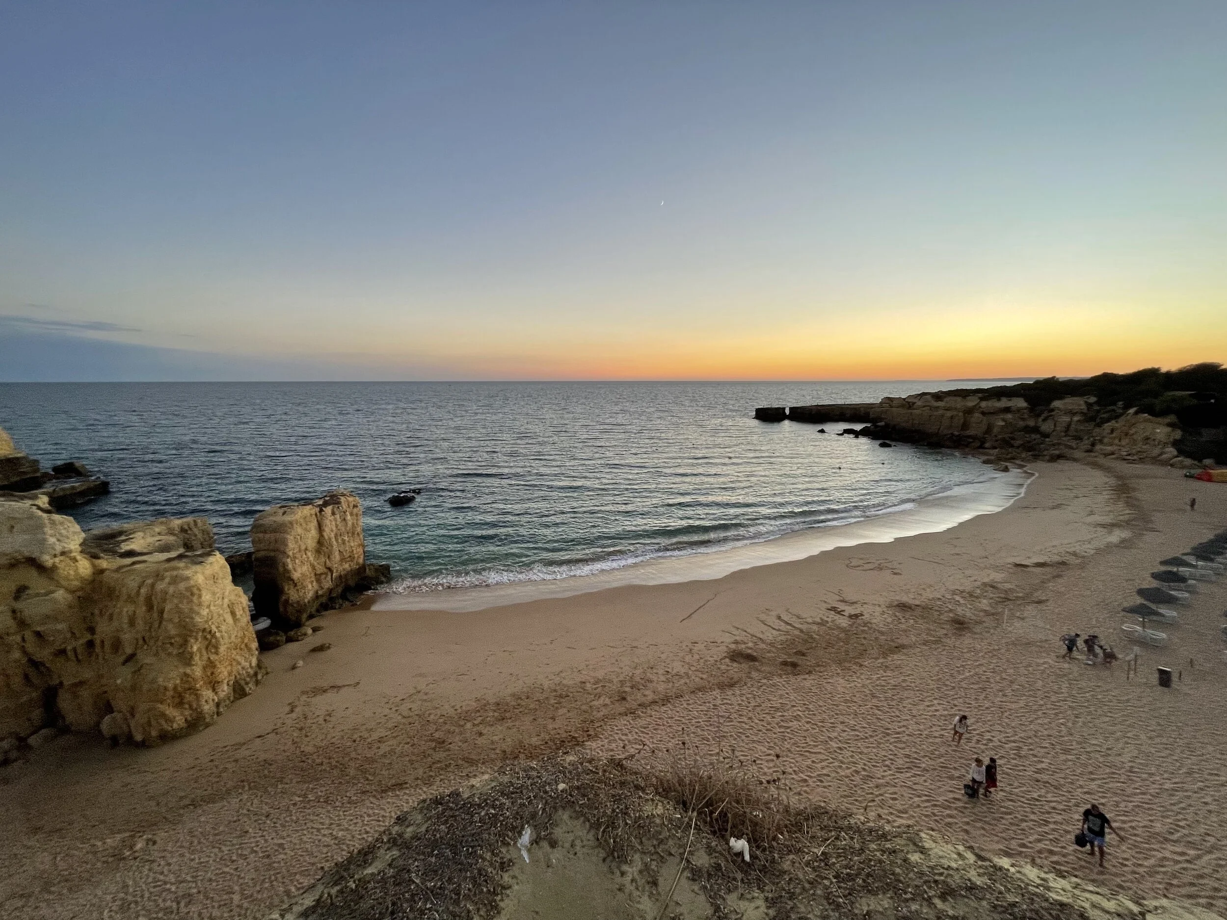 image of a beach with the sun setting over the horizon