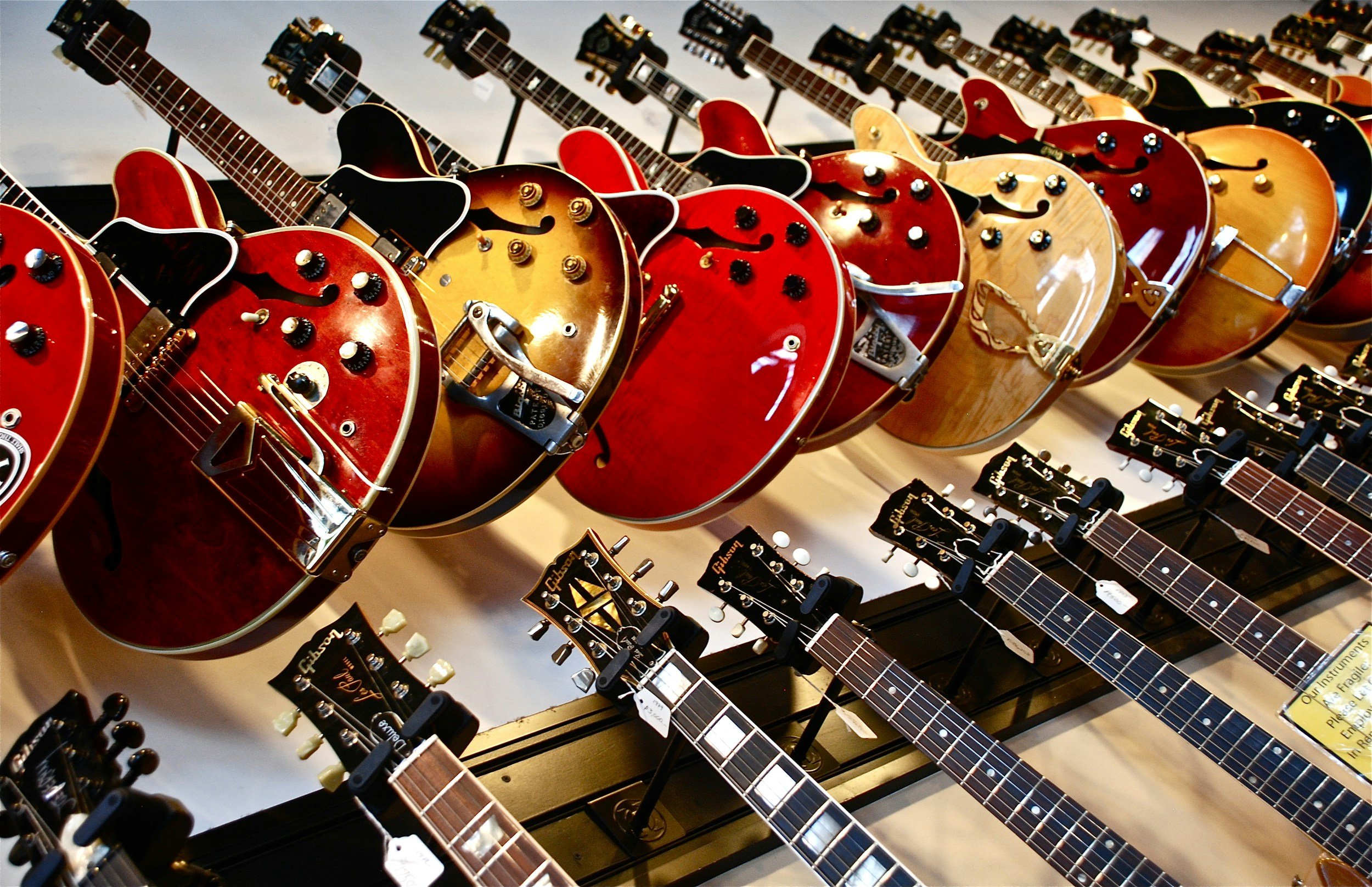 Display of multiple vintage electric and acoustic guitars arranged on a rack in a music store.