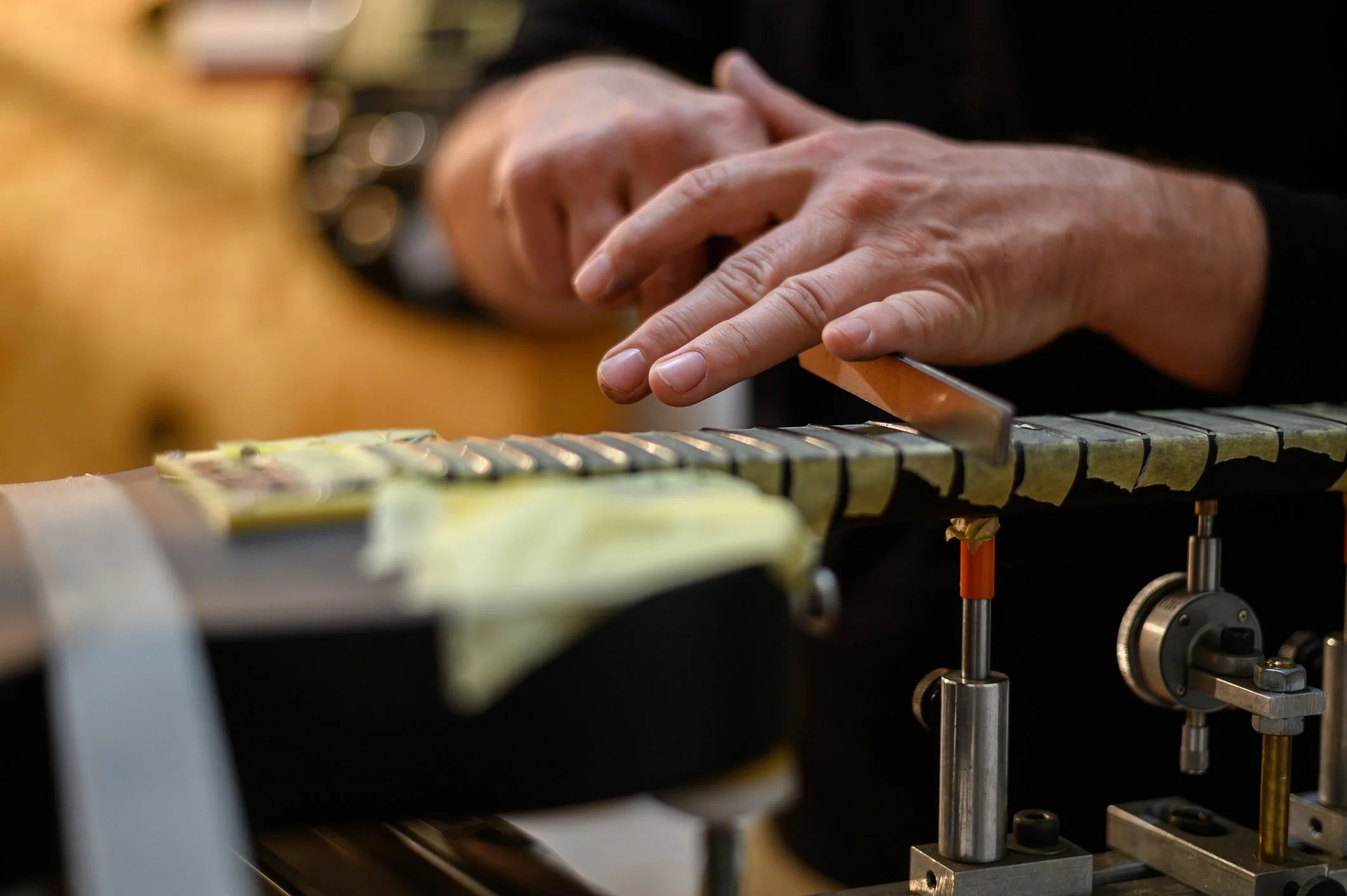 Leveling the frets on a guitar with tape for protection.