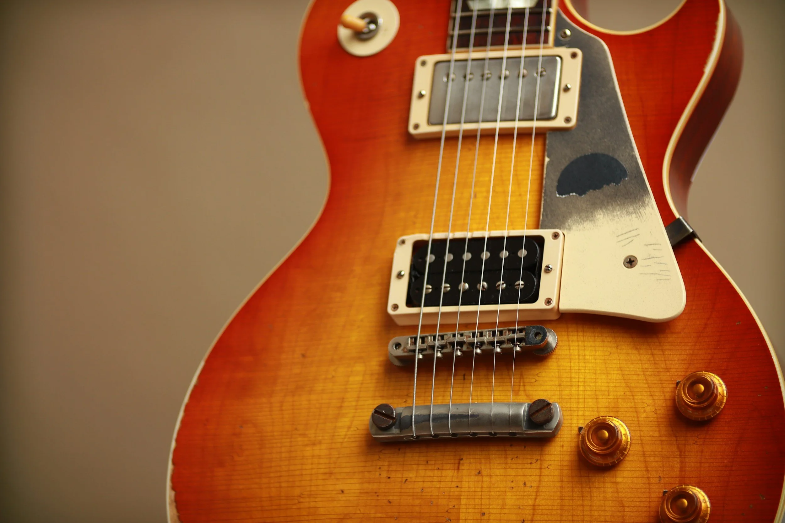 Close-up of a vintage orange electric guitar with visible pickguard, pickups, strings, control knobs, and tuning pegs.