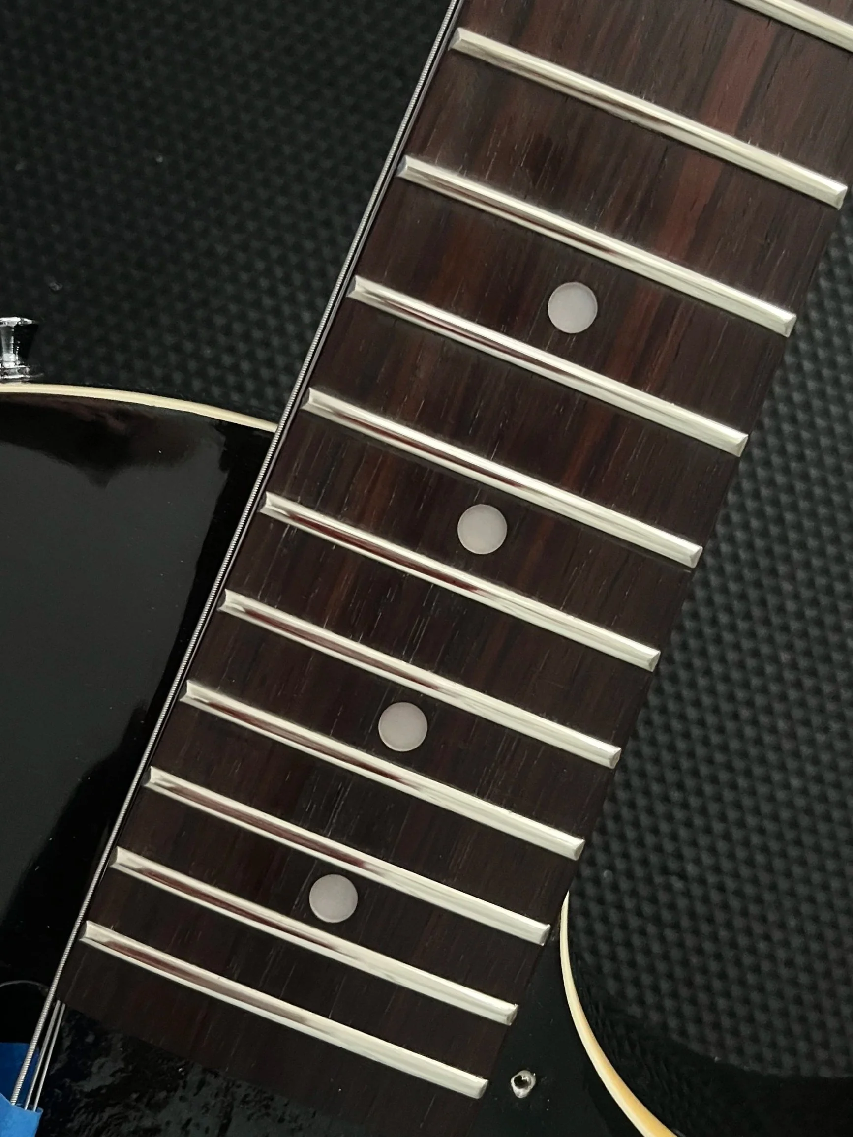 Close-up of a guitar neck showing fretboard and  frets leveled and polished