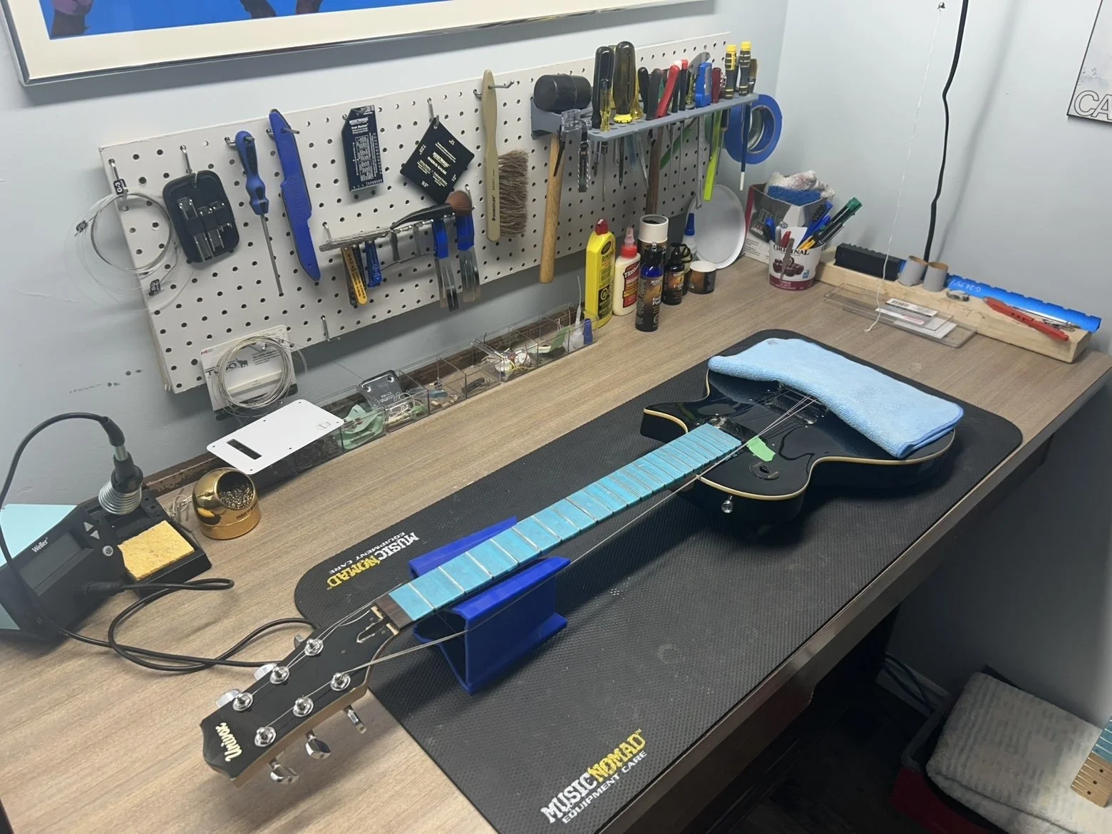 An electric guitar on a workbench is getting a fret leveling job.