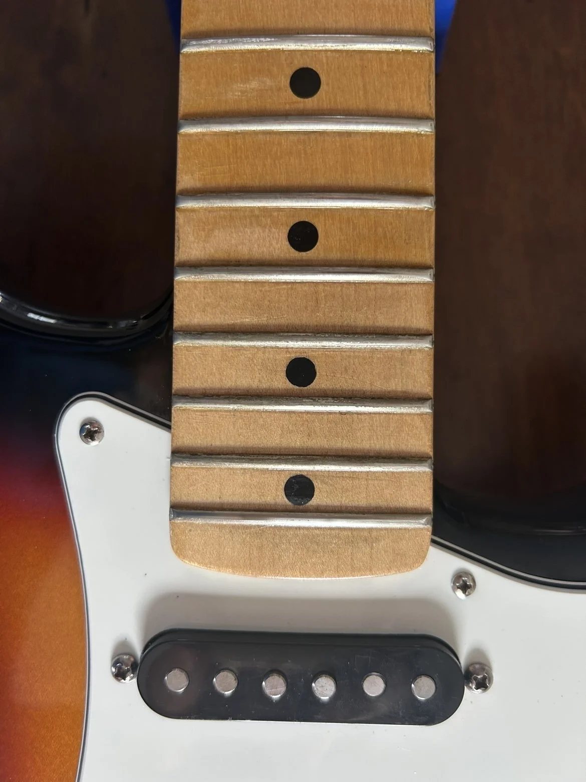 Part -2 - Close-up of a guitar neck with frets and a maple fretboard cleaned and polished.