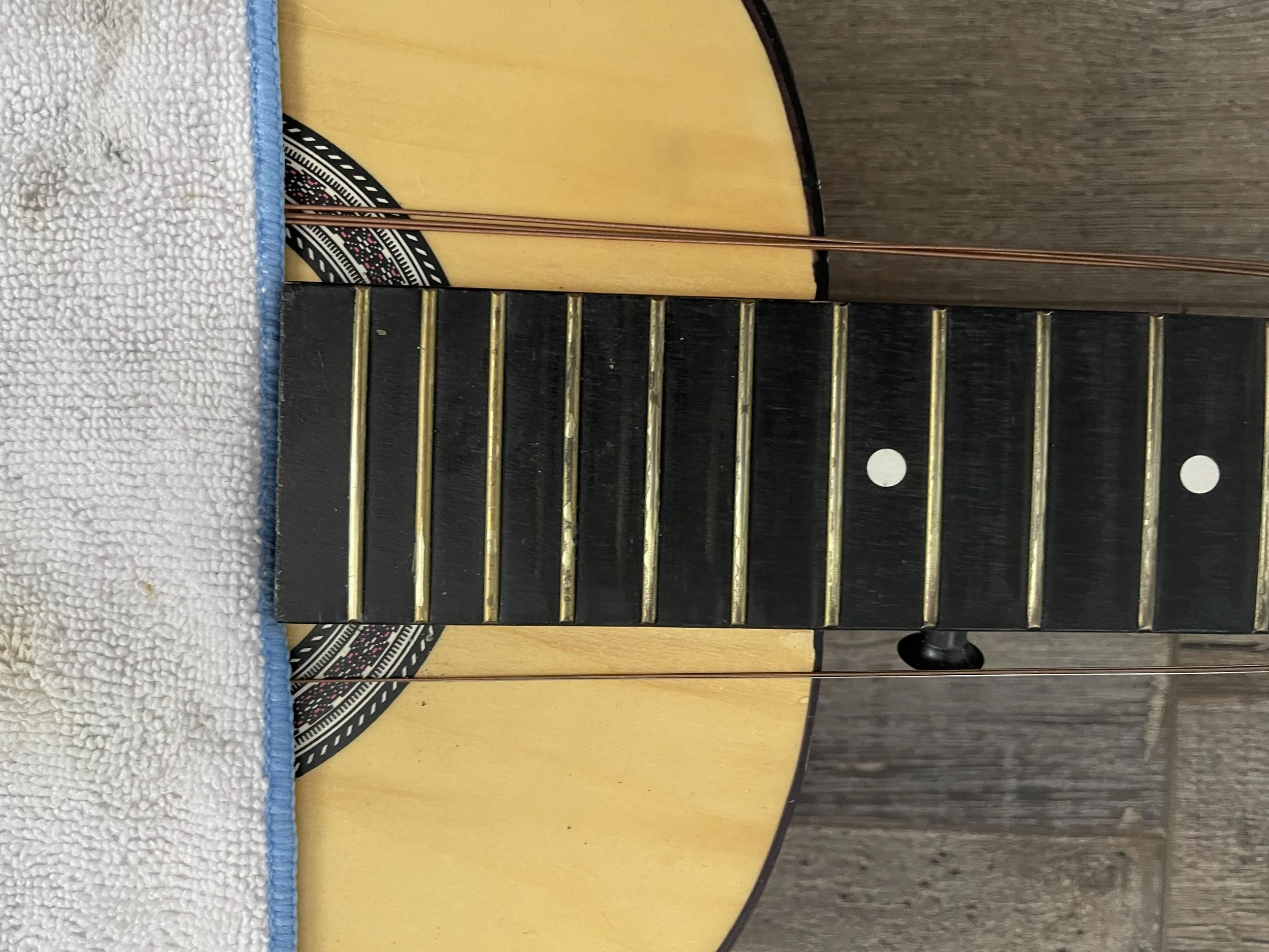 Dirty, grimy fretboard and frets about to be cleaned and polished.