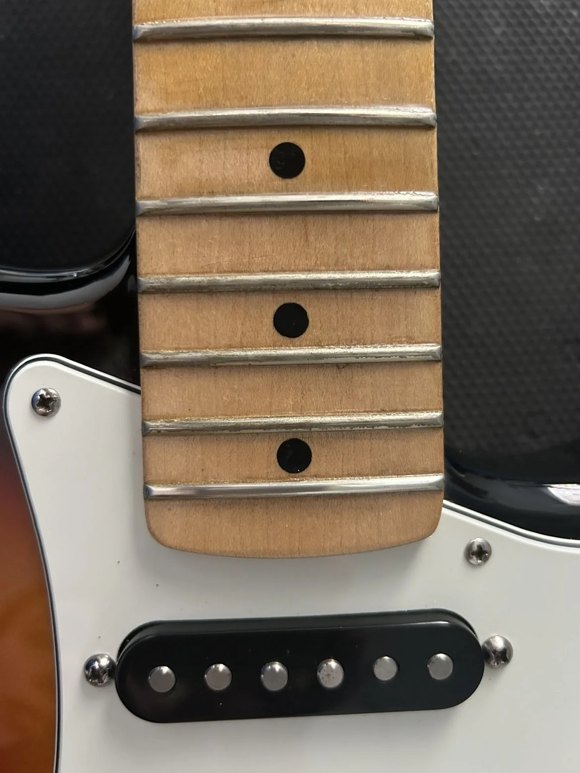 Part -1 -Close-up of an electric guitar neck showing dirty and used frets, and a maple fretboard.