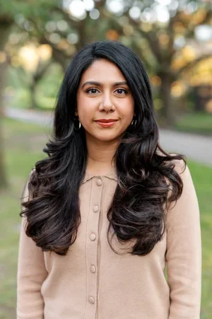 Samina Qureshi, registered dietitian and founder, smiling wearing a beige buttoned cardigan